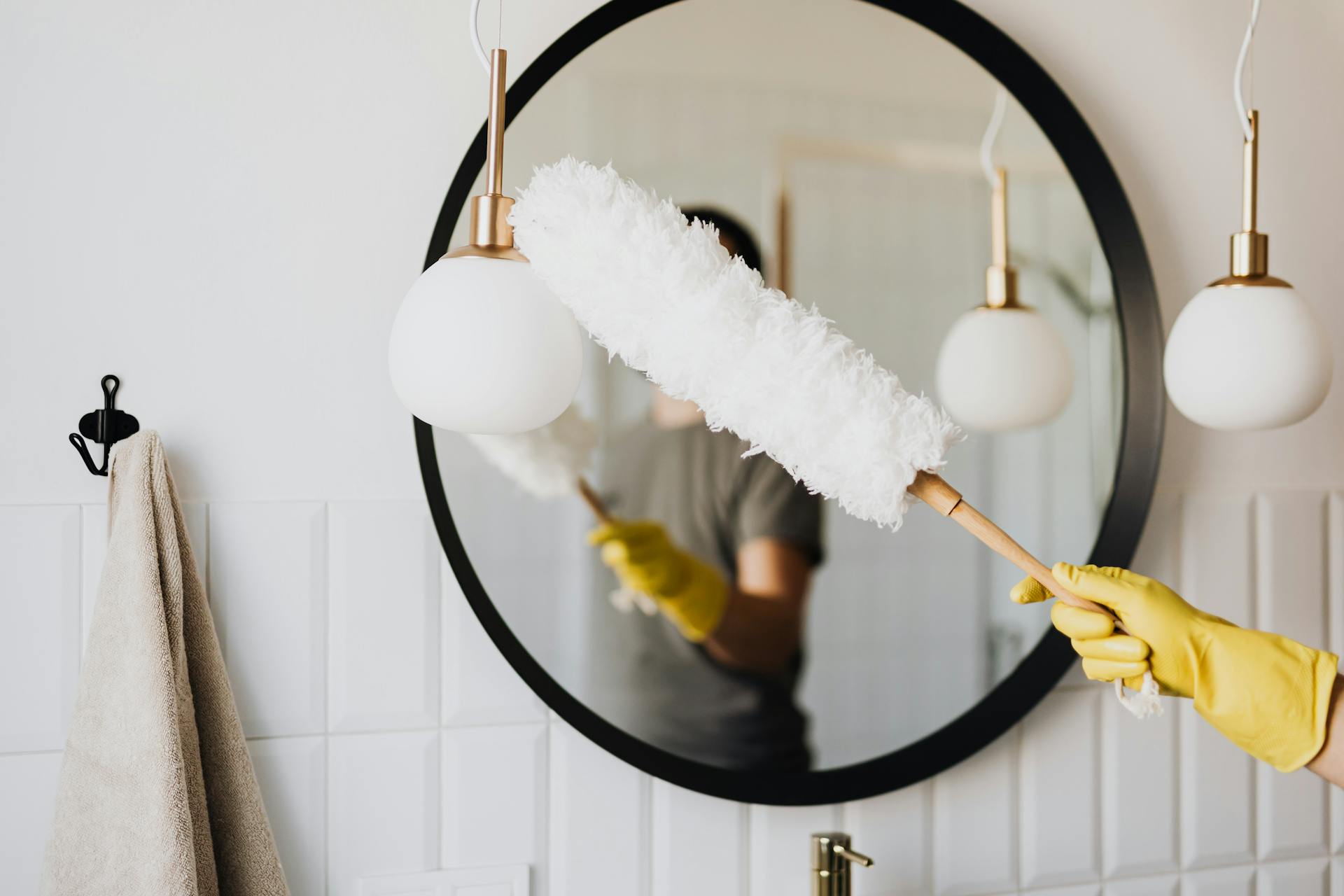 Eine Frau staubt eine Lampe ab | Quelle: Pexels