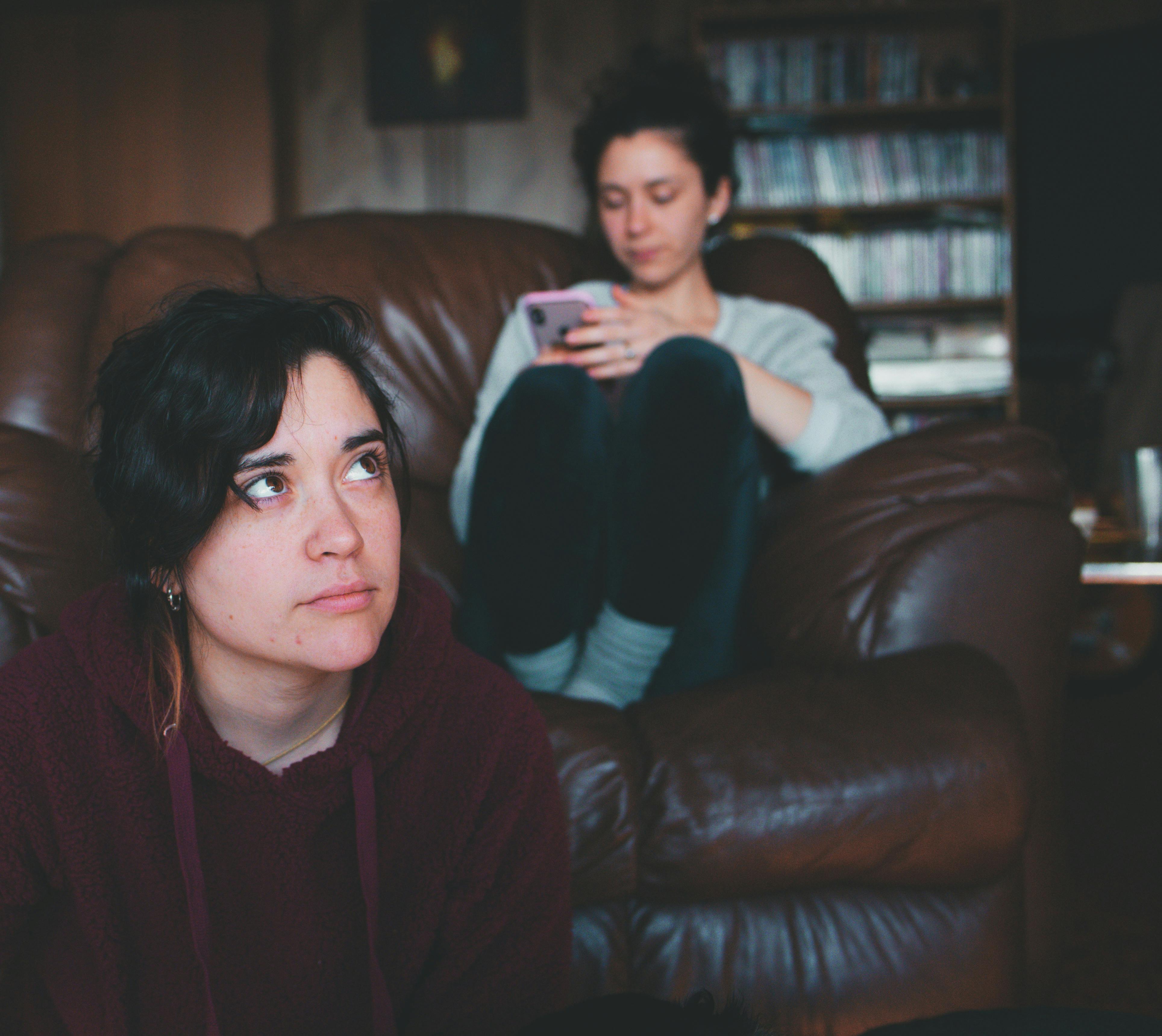 Eine Frau sitzt auf dem Boden, während eine andere auf der Couch sitzt | Quelle: Pexels