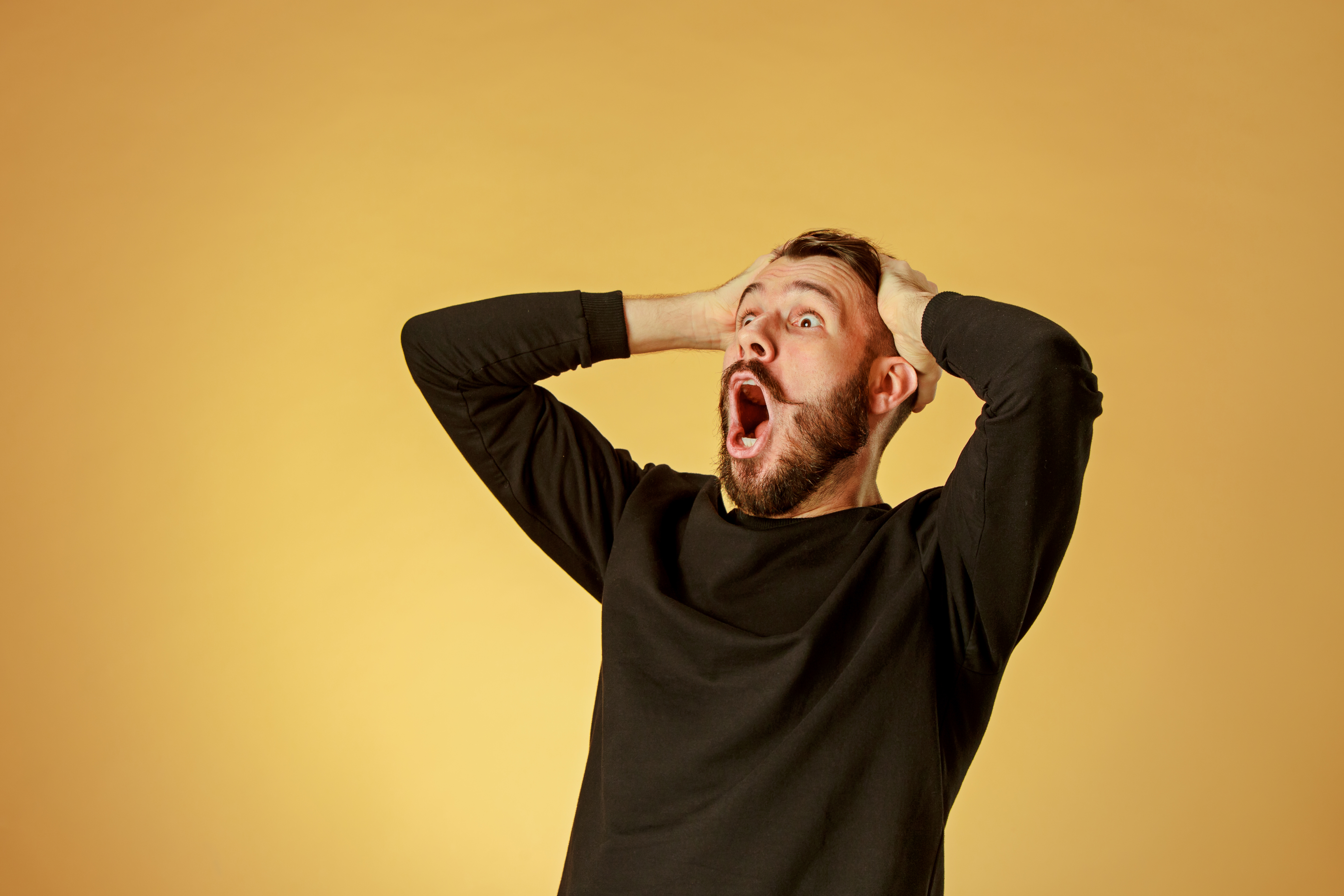 Zszokowany mężczyzna z rękami na głowie | Źródło: Shutterstock