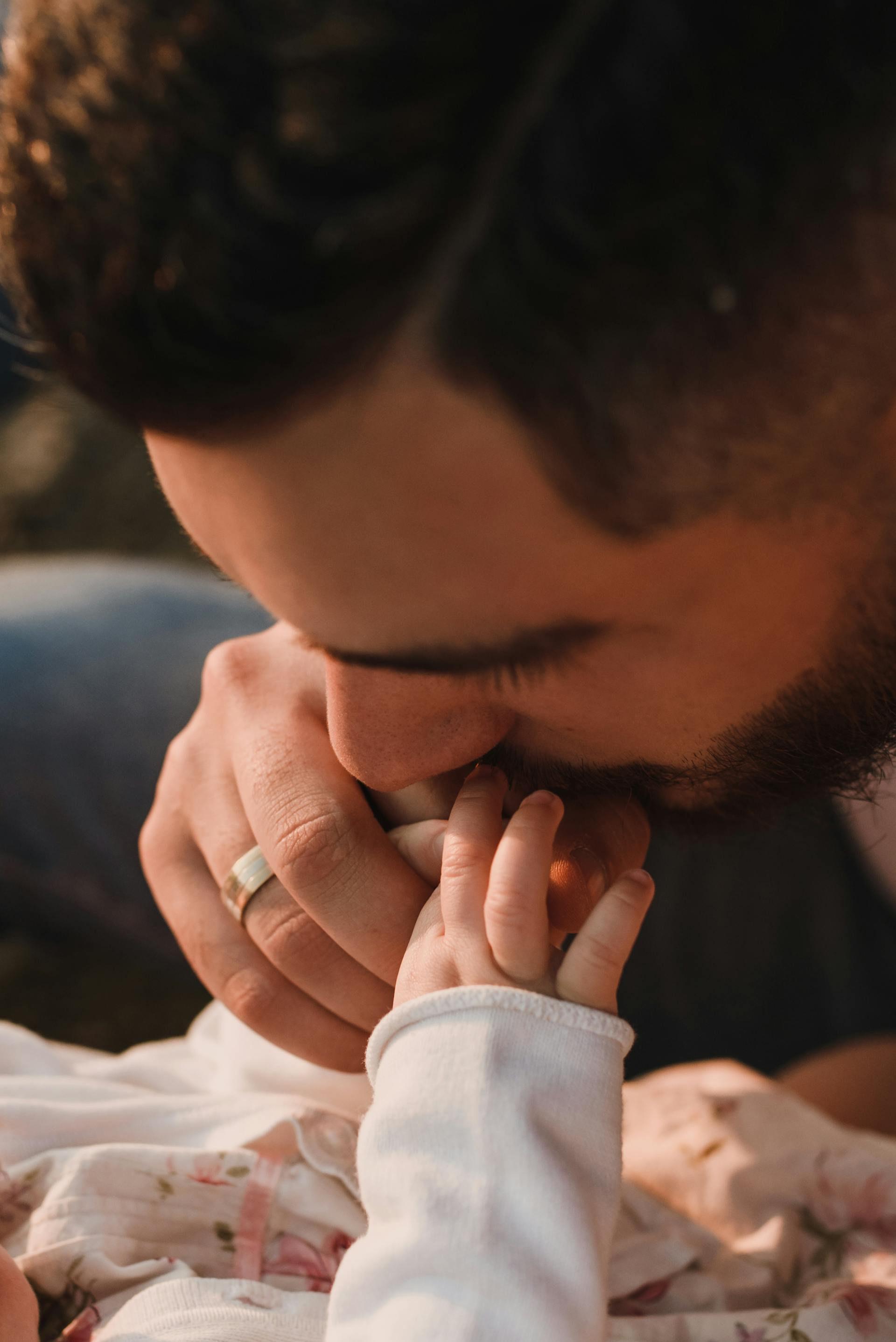 Eine Nahaufnahme eines Vaters, der die Hand seines Babys küsst | Quelle: Pexels