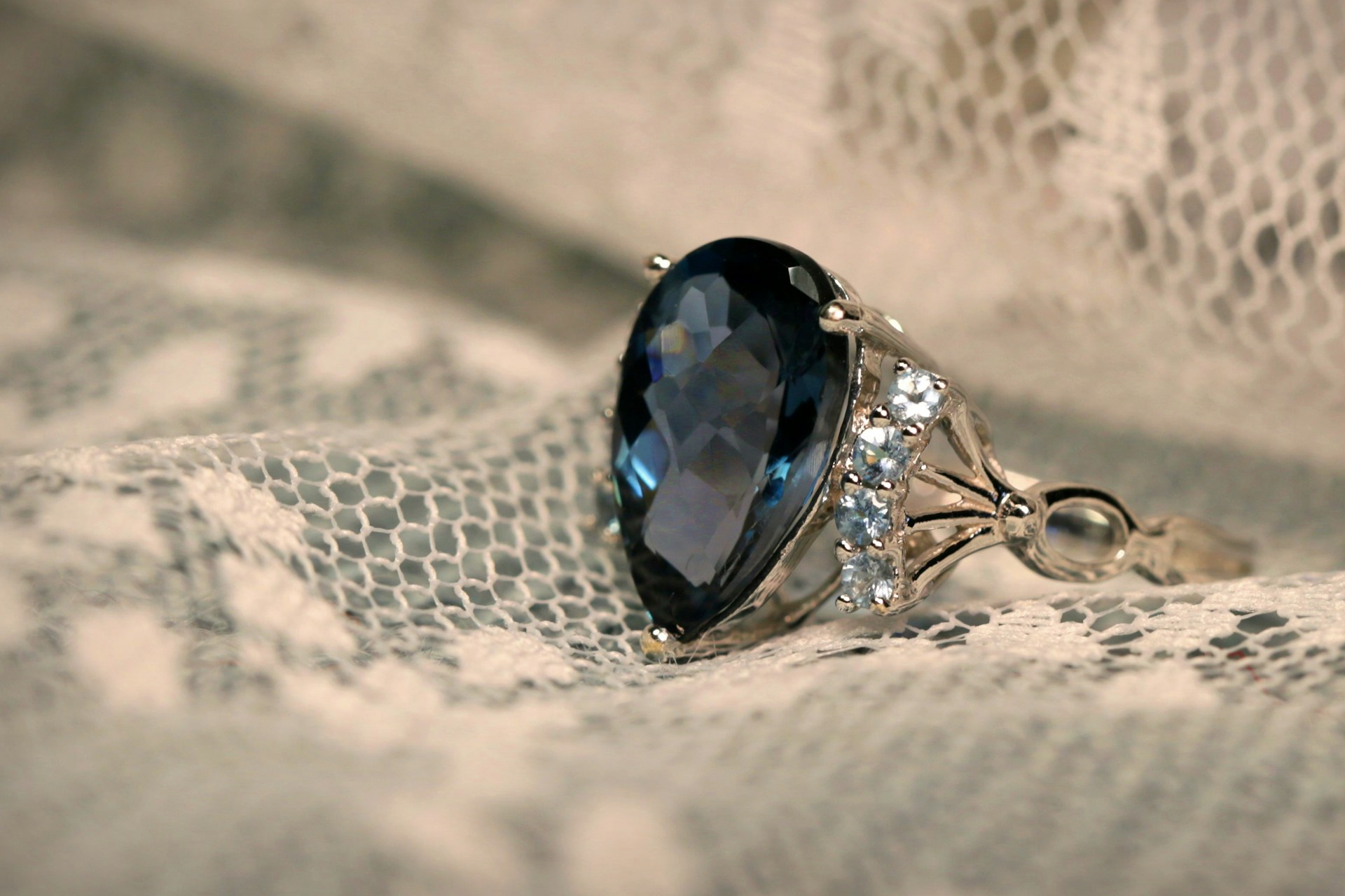 Ein mit Steinen besetzter Ring auf einem weißen Spitzentuch | Quelle: Unsplash