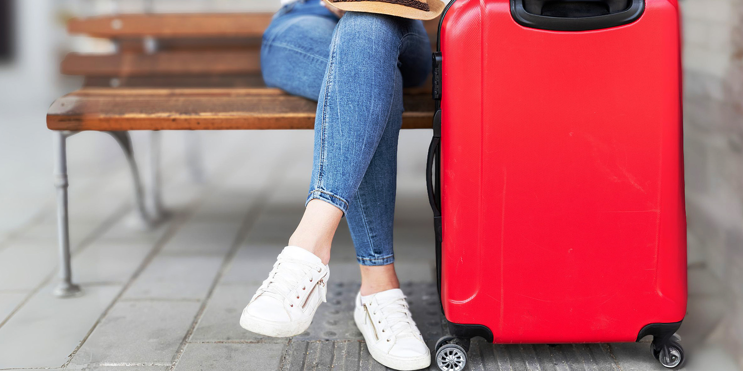 Eine Person, die neben einem roten Koffer sitzt | Quelle: Freepik