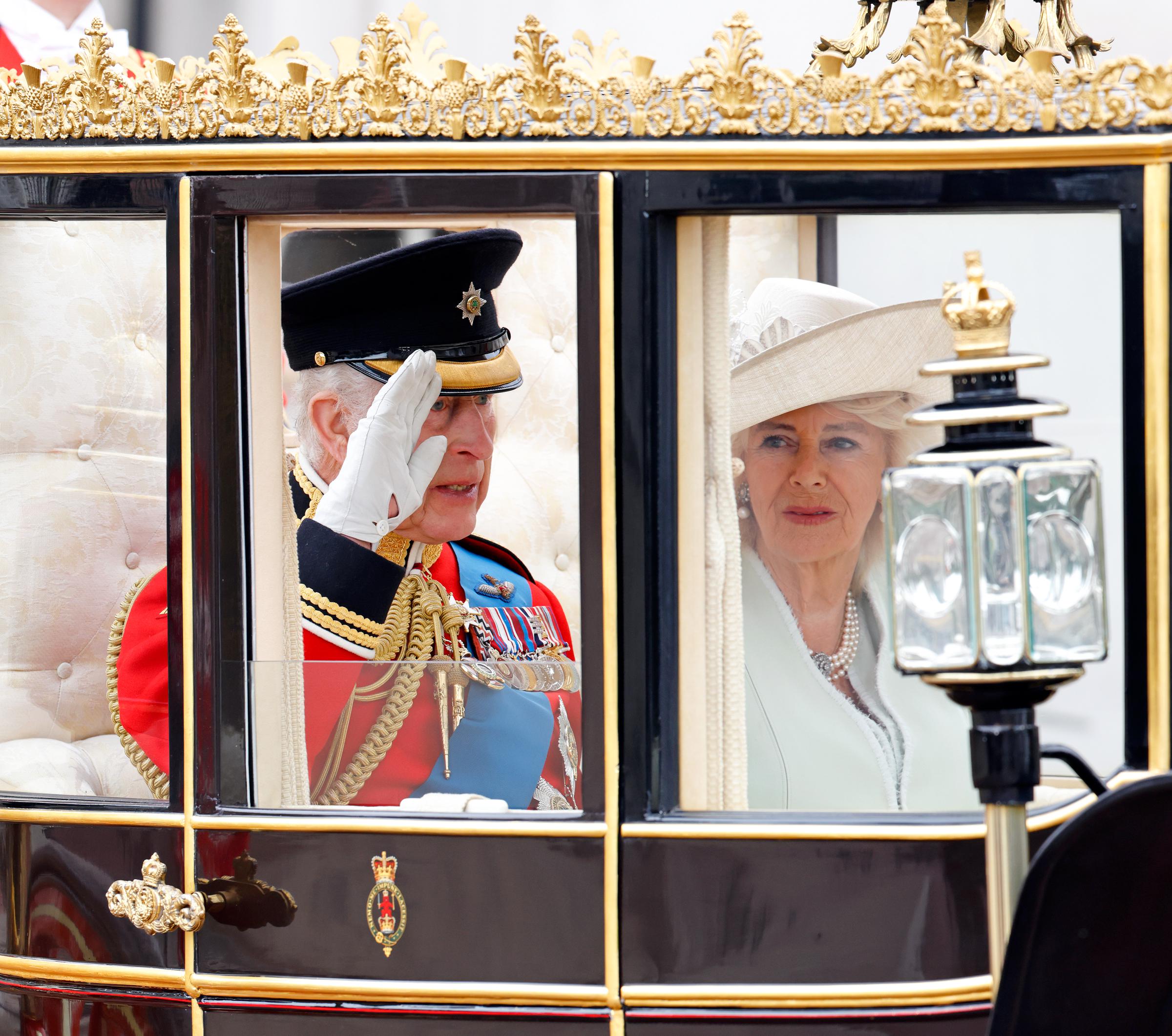König Charles III. salutiert in der schottischen Staatskutsche neben Königin Camilla, als sie den Buckingham Palace auf dem Weg zur Horse Guards Parade am 15. Juni 2024 verlassen | Quelle: Getty Images