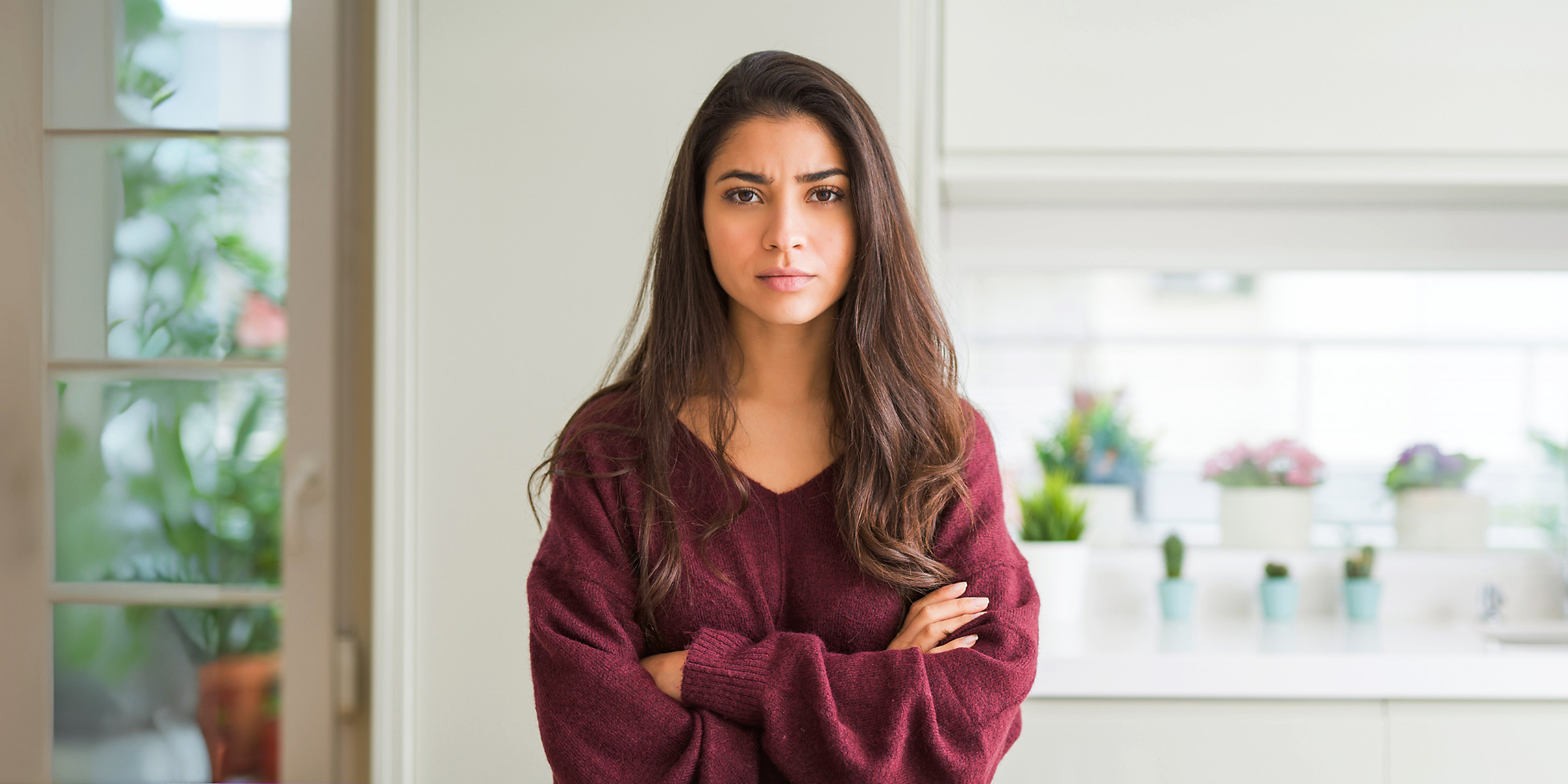 Eine verärgert aussehende Frau, die mit verschränkten Armen dasteht | Quelle: Shutterstock