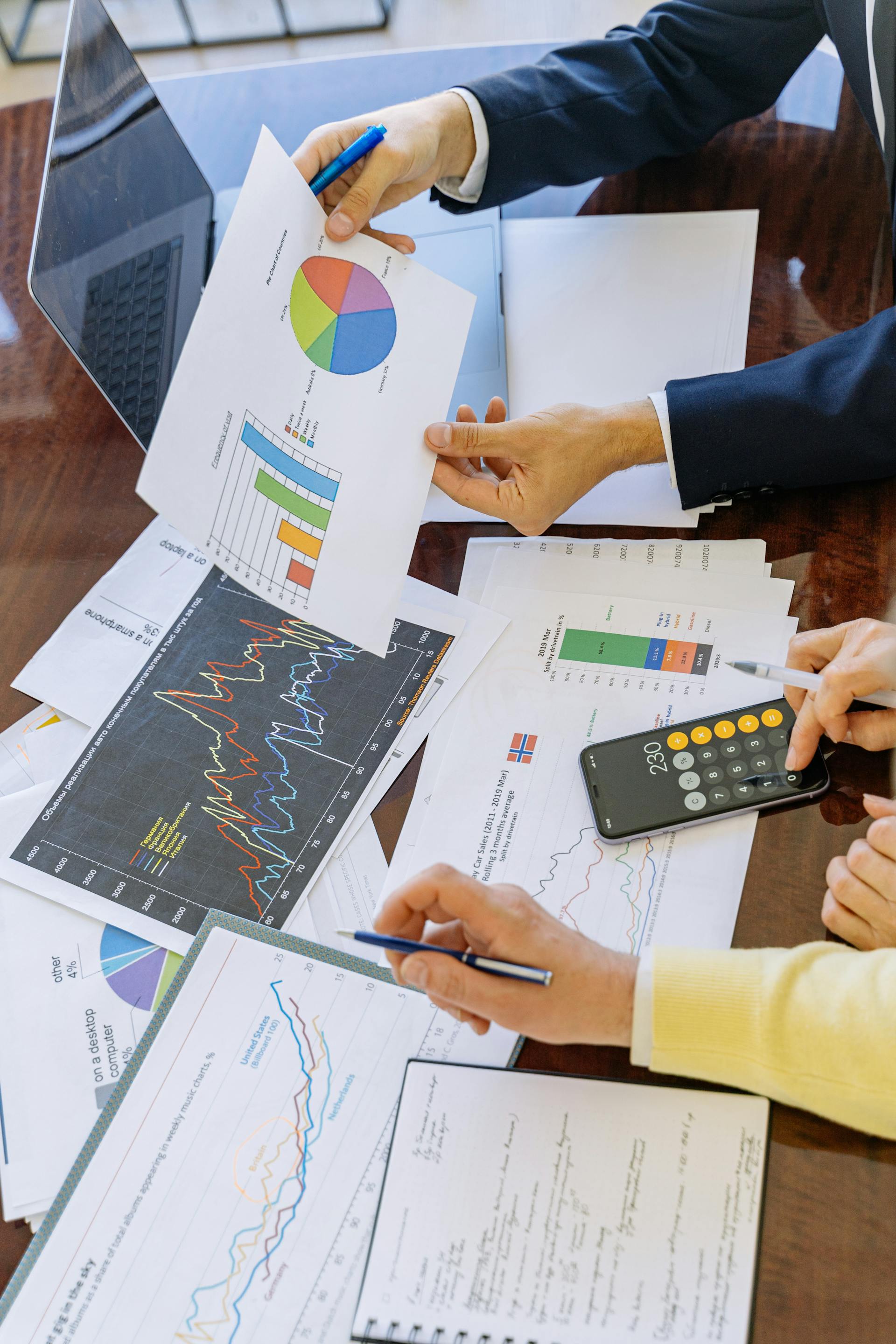 Nahaufnahme von zwei Personen, die in einem Büro Diagramme und Tortendiagramme analysieren | Quelle: Pexels