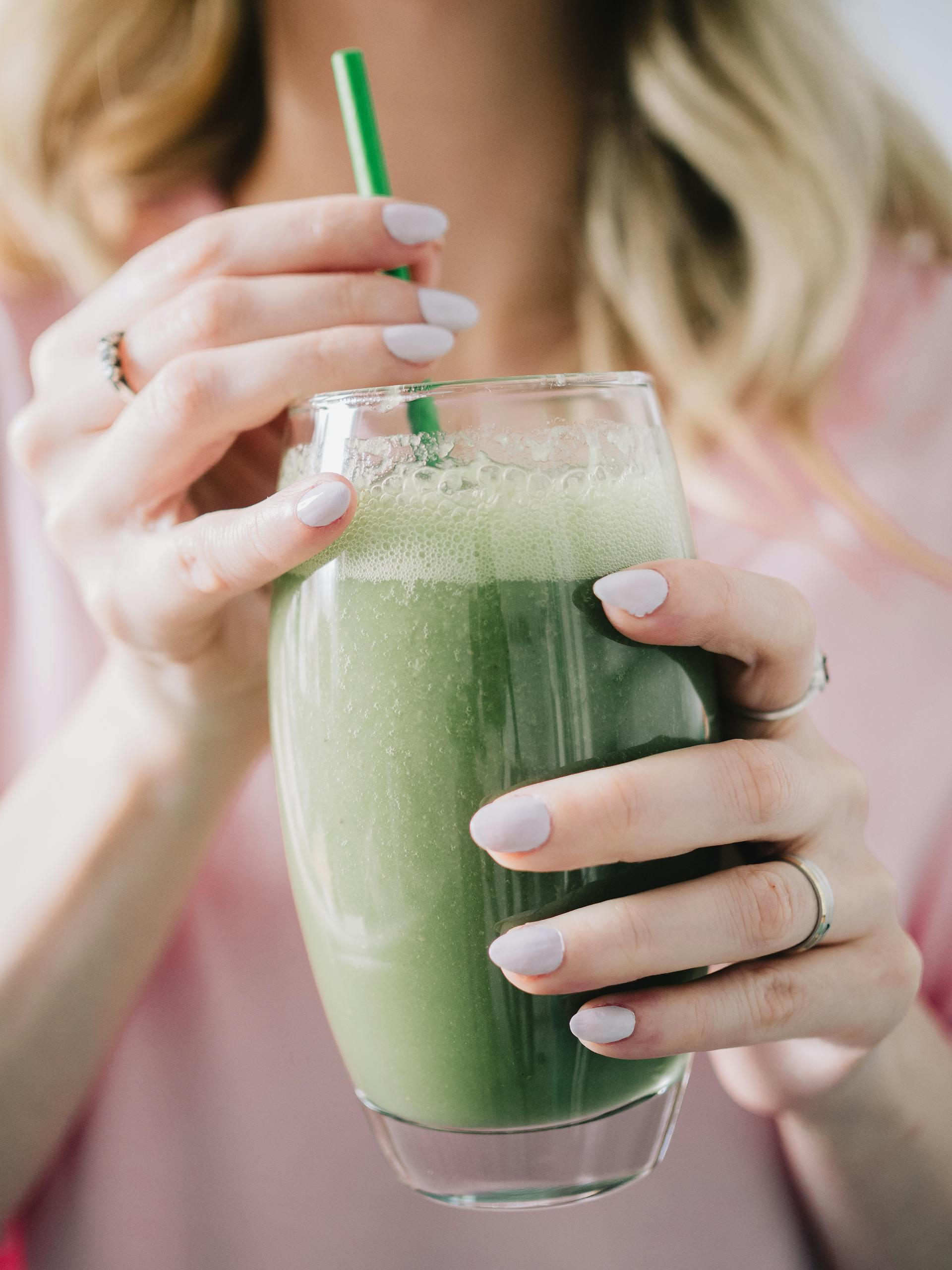 Eine Frau hält ein Glas mit grünem Smoothie | Quelle: Pexels