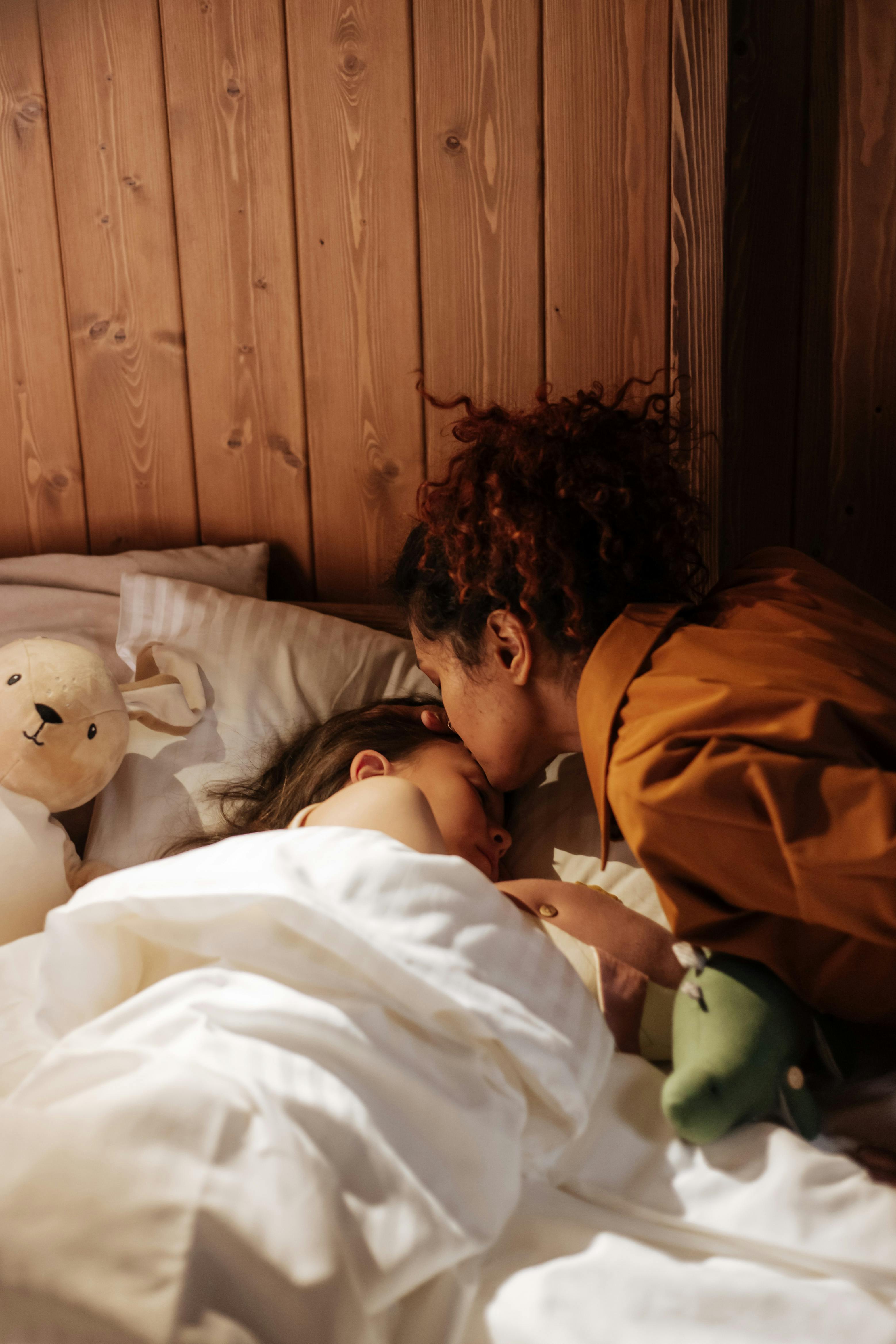 Eine Mutter, die ihre Tochter ins Bett bringt | Quelle: Pexels