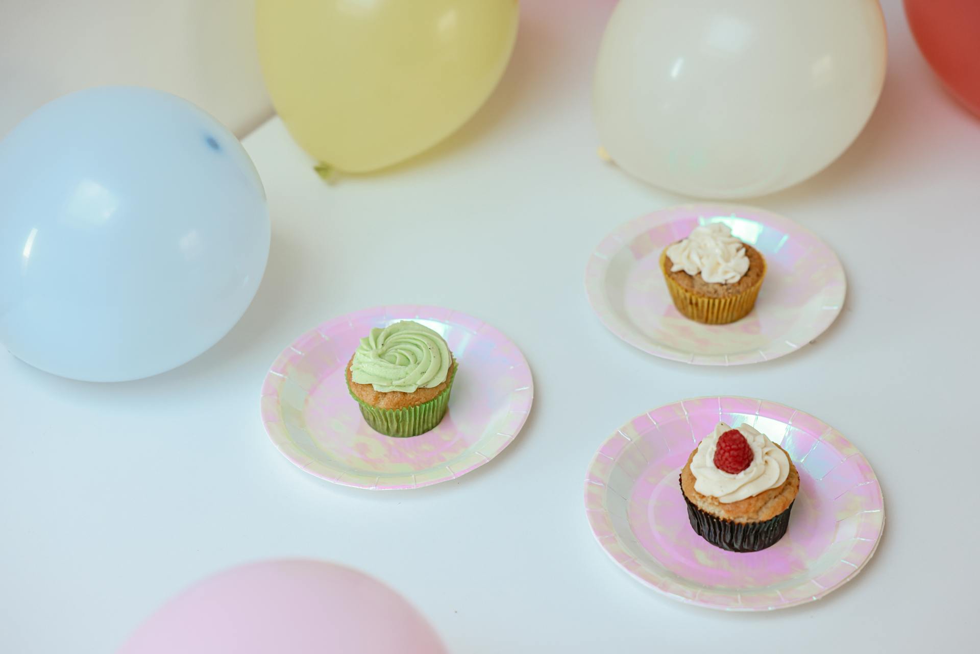 Cupcakes und bunte Luftballons auf einem Tisch | Quelle: Pexels