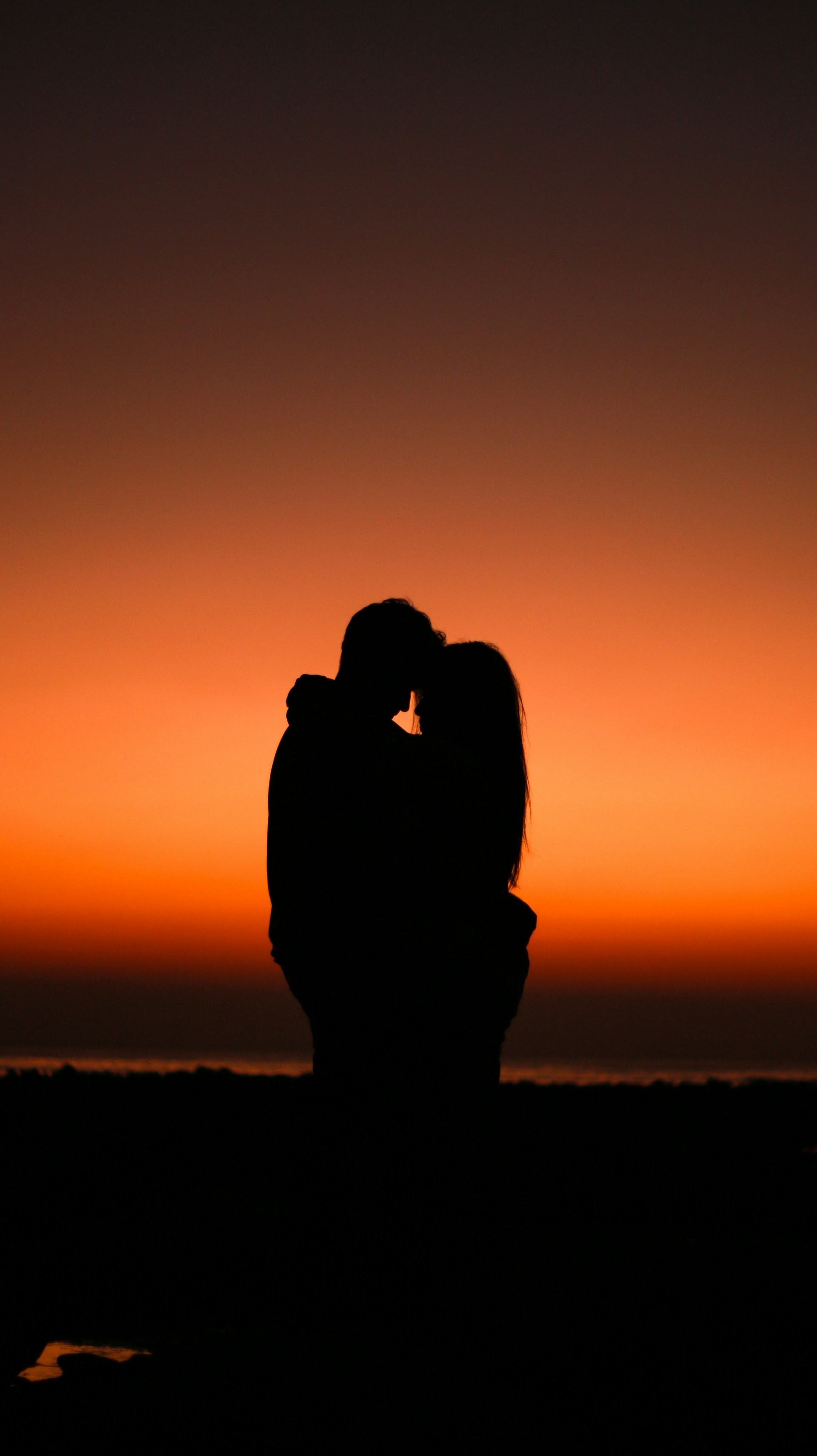 Silhouette eines sich umarmenden Paares an einem goldenen Abend | Quelle: Unsplash