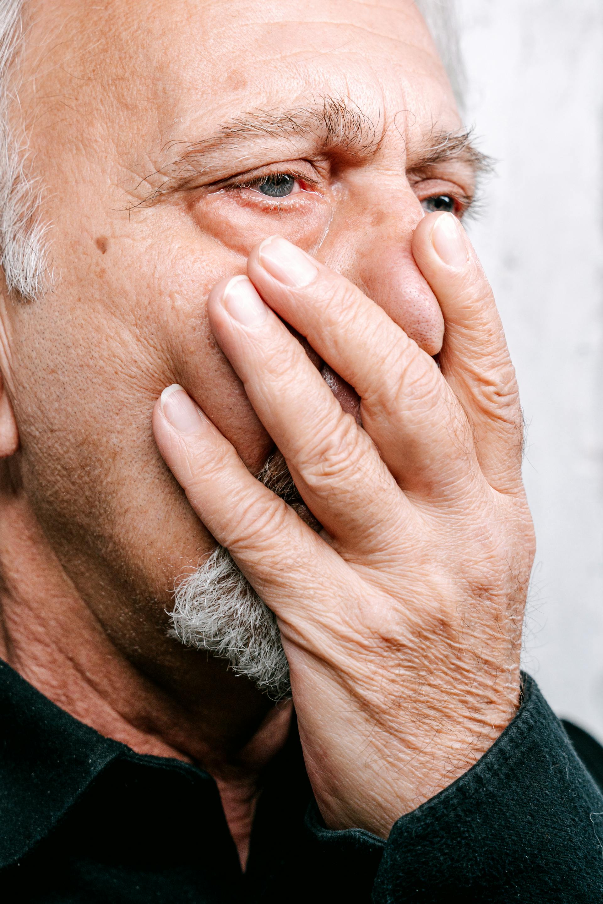 Ein Mann, der seinen Mund mit einer Hand bedeckt | Quelle: Pexels