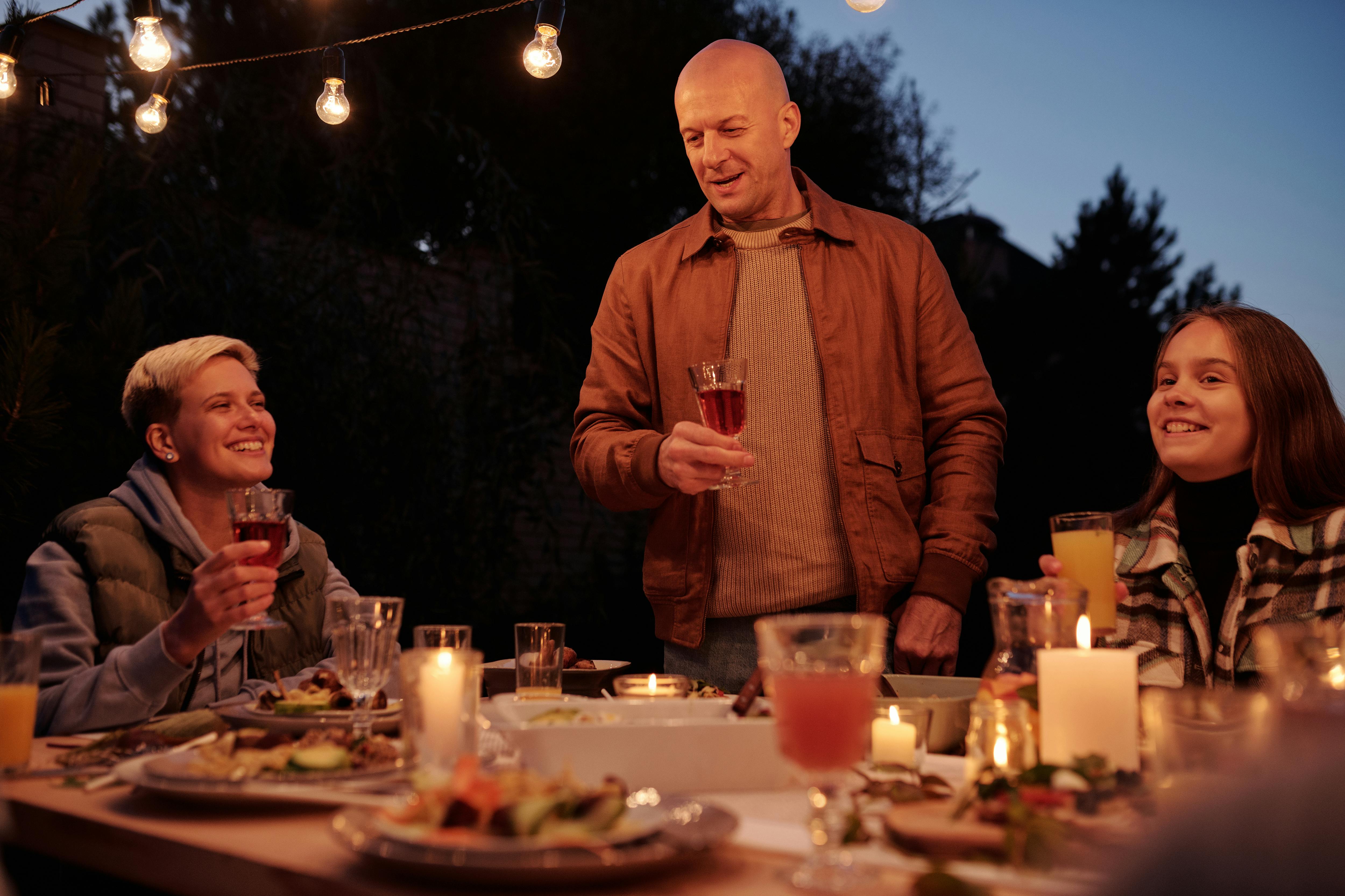 Ein Mann stößt beim Familienessen an | Quelle: Pexels