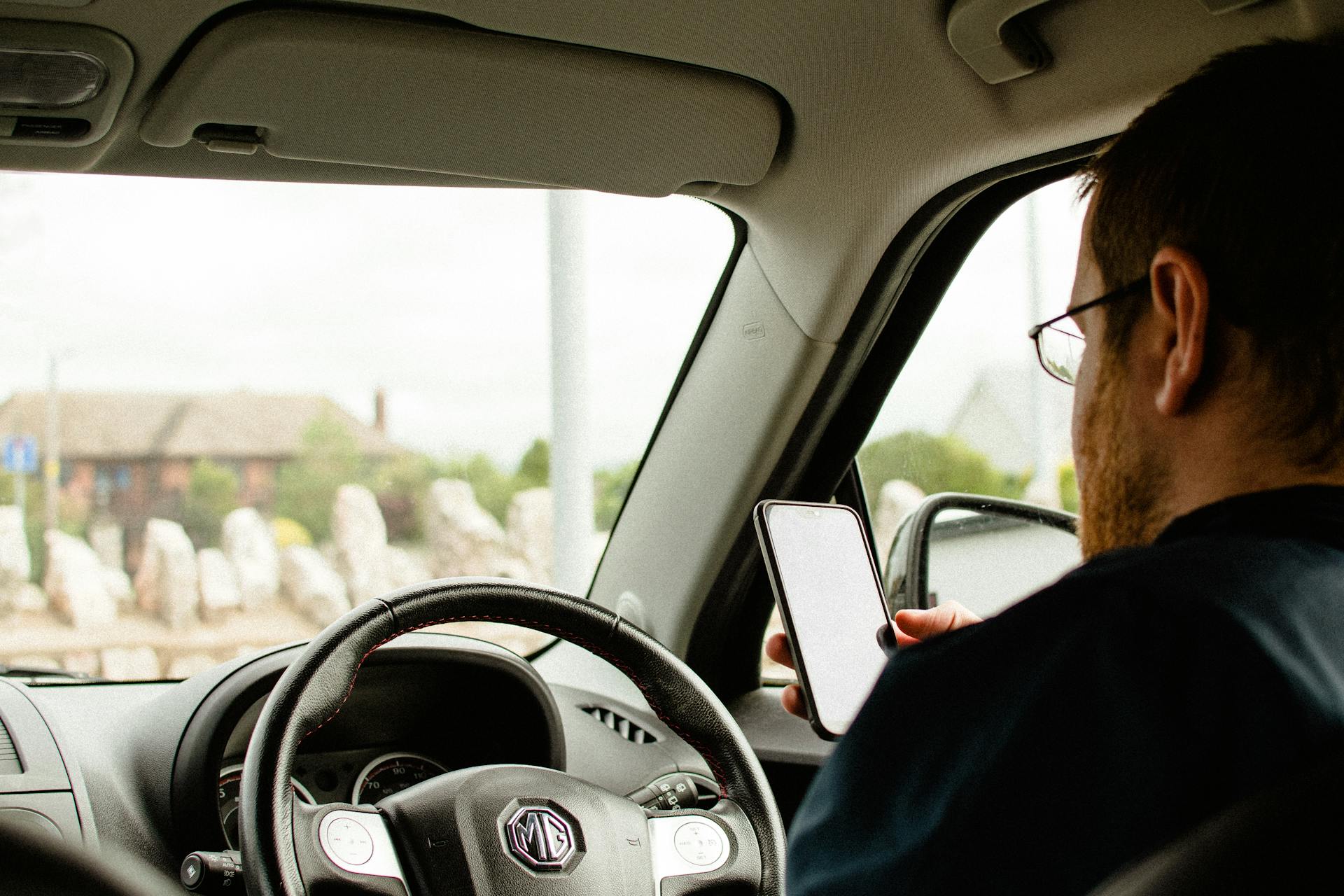 Ein Mann hält sein Telefon in der Hand, während er in seinem Auto sitzt | Quelle: Pexels