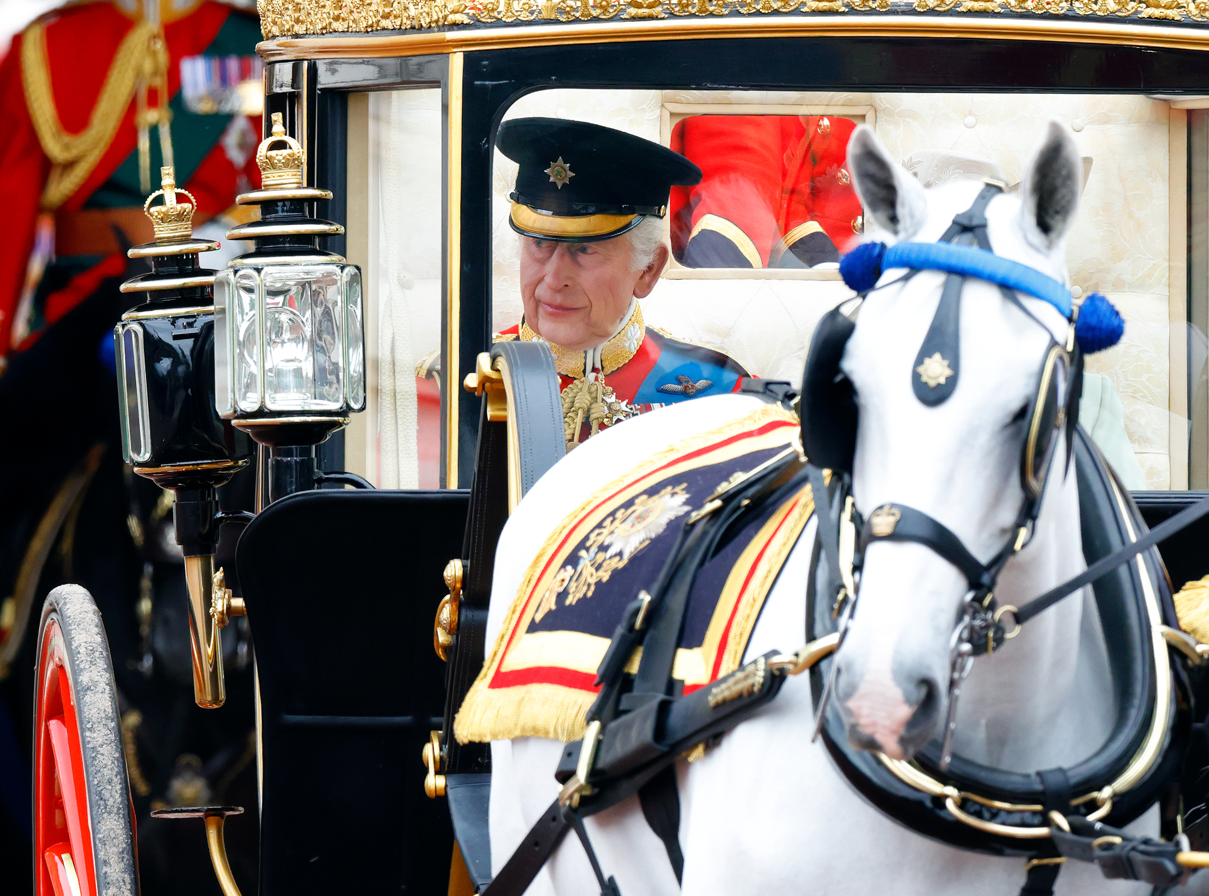 König Karl III. erscheint feierlich und gelassen in seiner Uniform der Irischen Garde, als er in der Staatskutsche zum Trooping the Colour 2024 reitet | Quelle: Getty Images