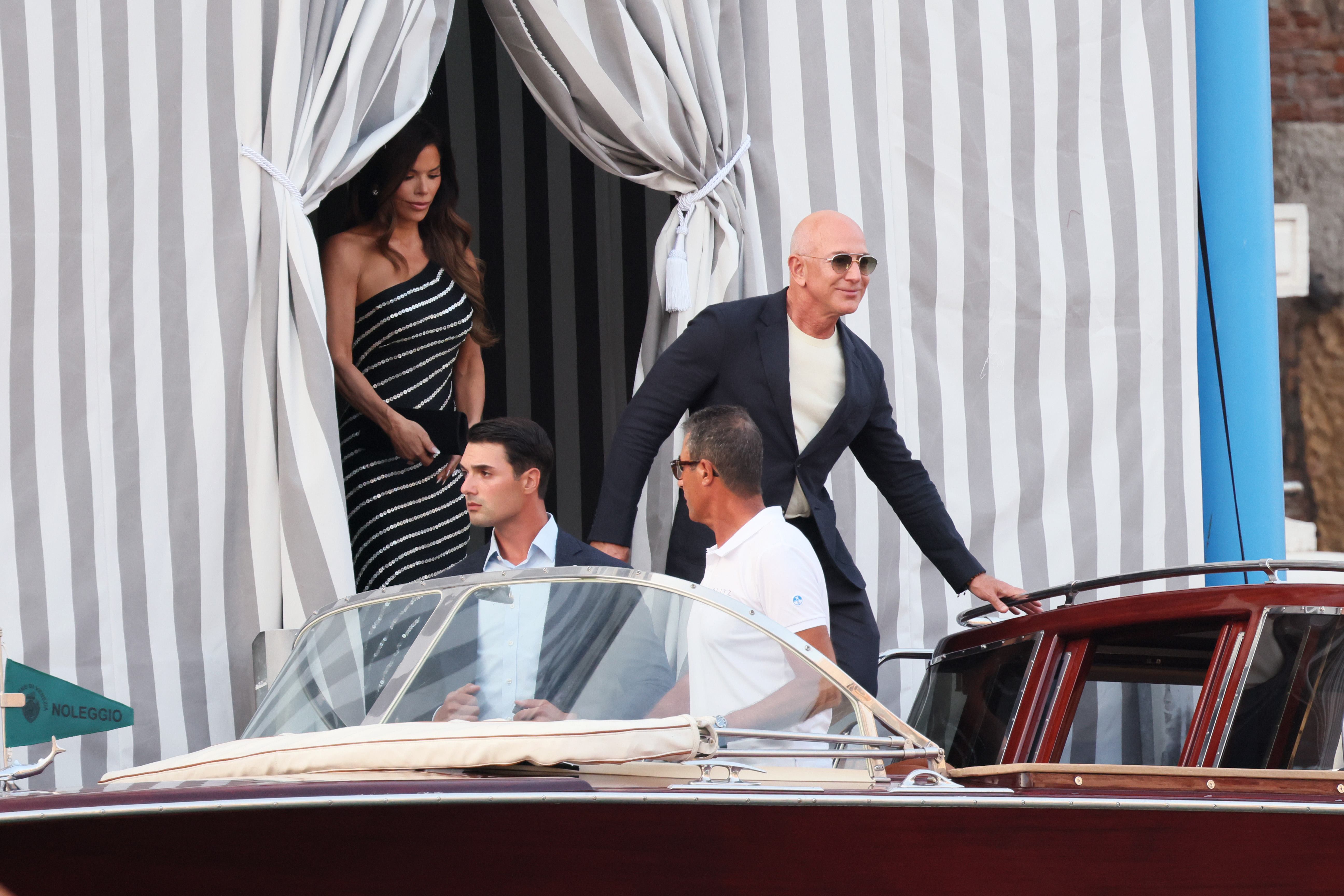 Jeff Bezos schreitet zu einem wartenden Boot, während hinter ihm Lauren Sanchez in ihrem Hotel in Venedig am 25. Juni 2025 vor ihrem Hochzeitswochenende erscheint | Quelle: Getty Images