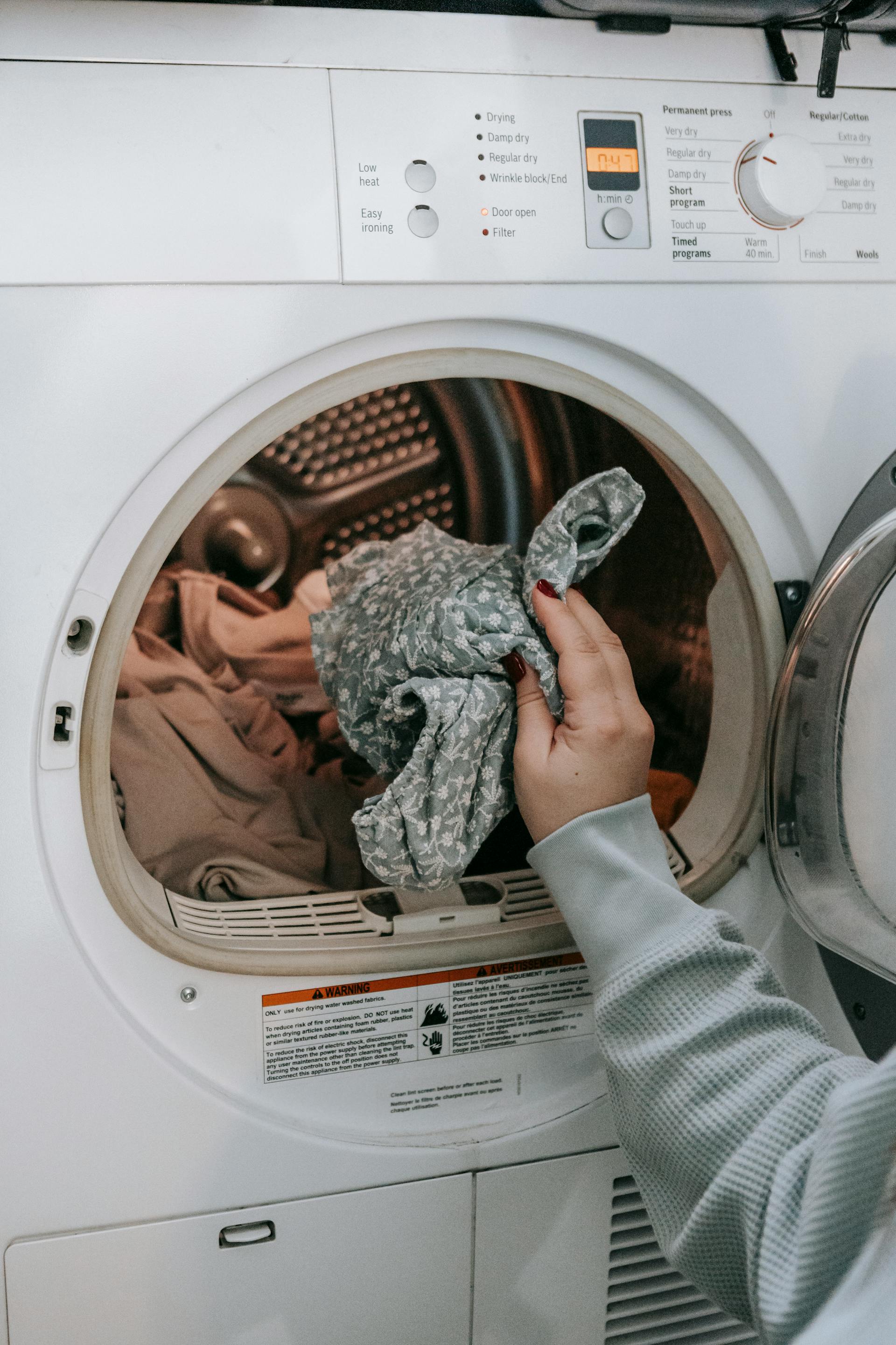Eine Frau, die Kleidung in eine Waschmaschine steckt | Quelle: Pexels