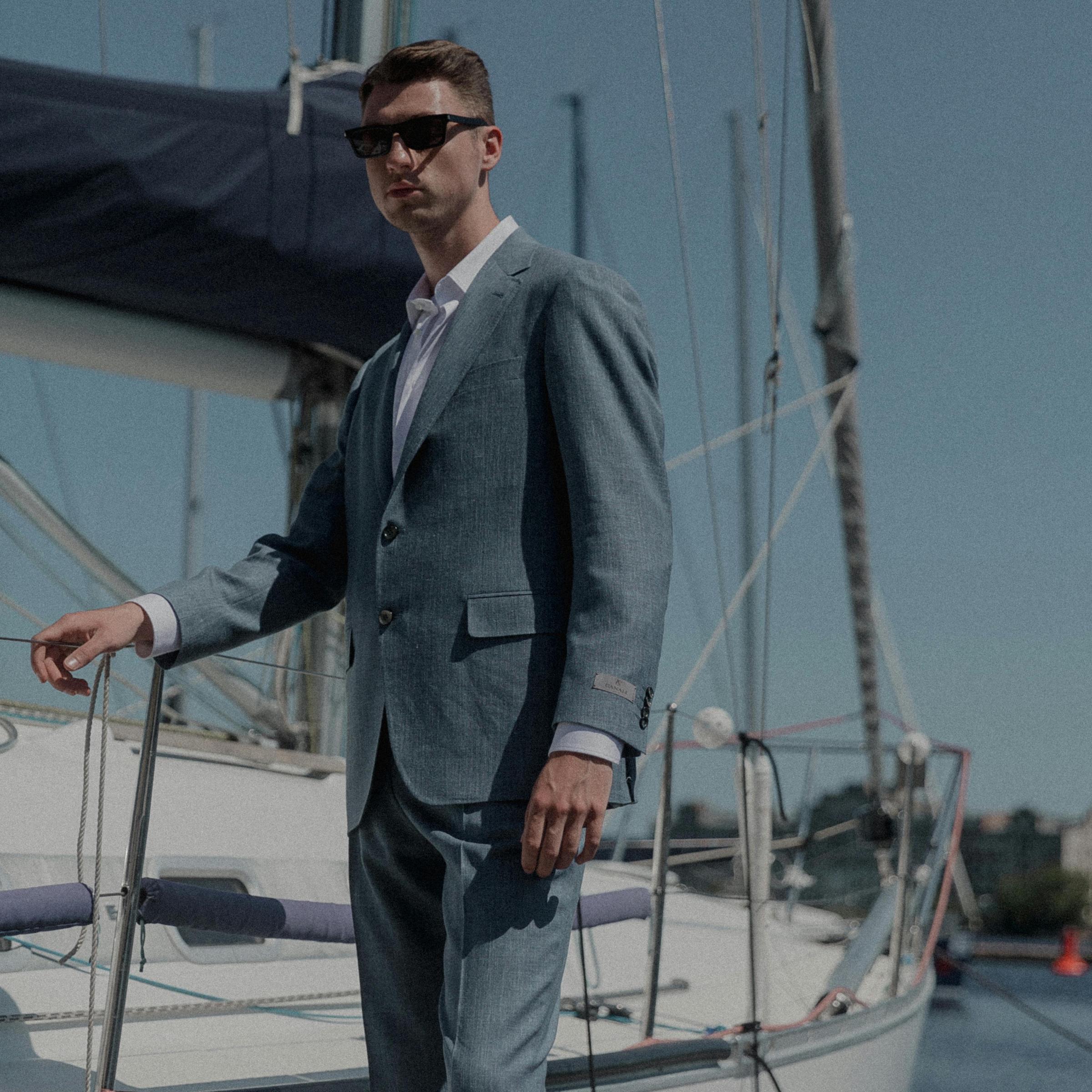 Ein elegant gekleideter Mann steht auf einem Yachtsteg | Quelle: Pexels