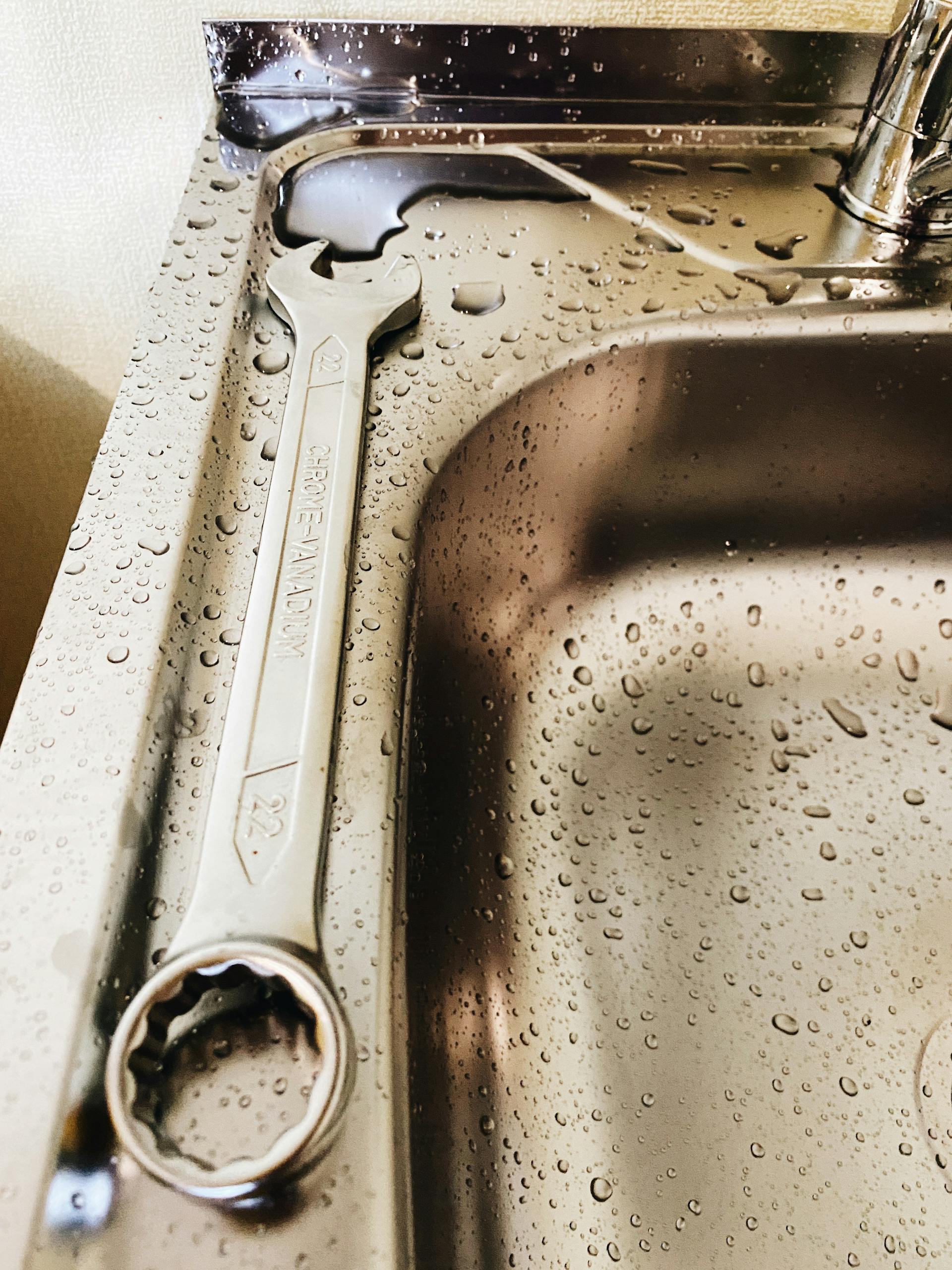 Schraubenschlüssel, der auf einem Waschbecken aus Edelstahl liegt | Quelle: Pexels