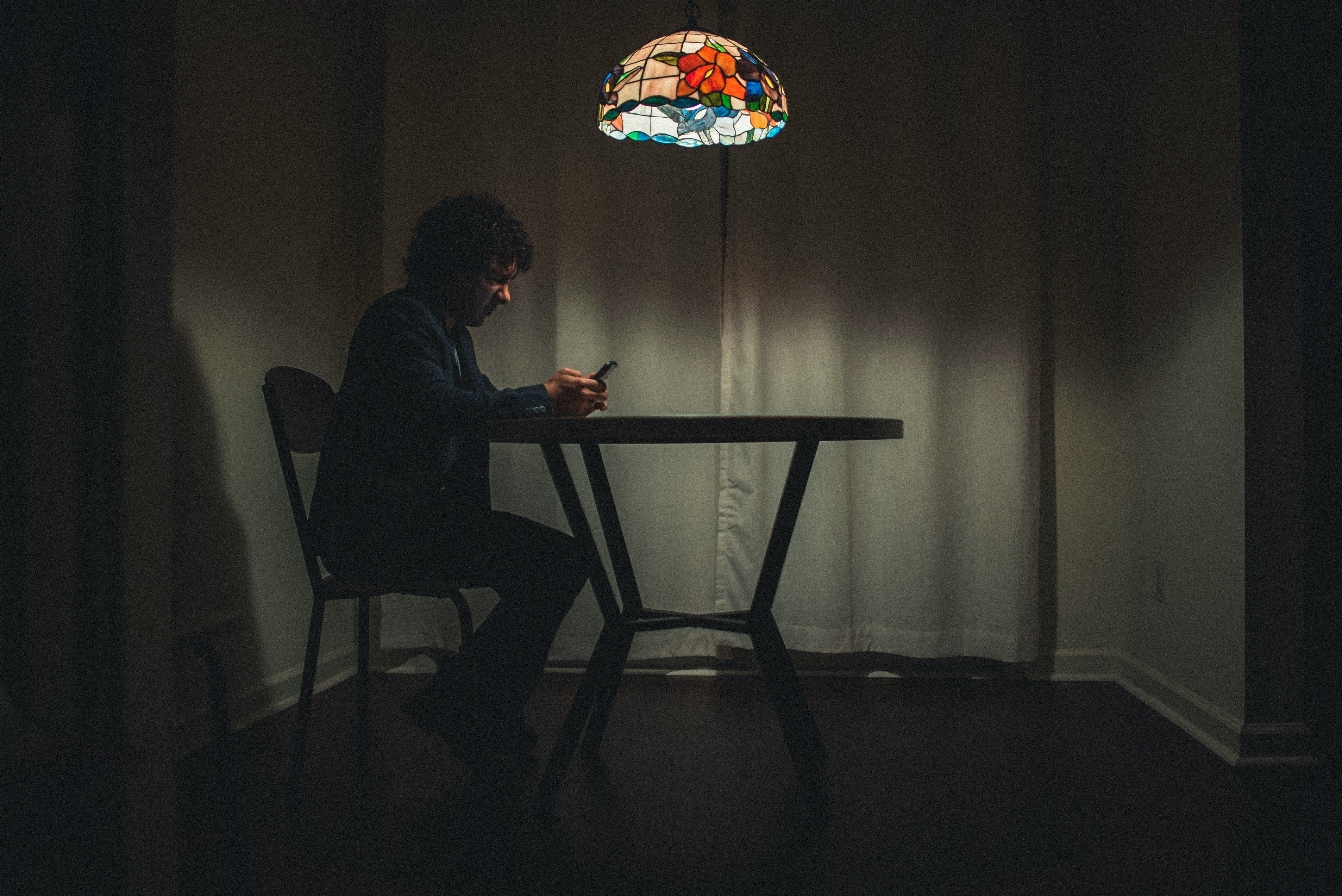 Ein Mann sitzt an einem Tisch und benutzt ein Handy | Quelle: Unsplash