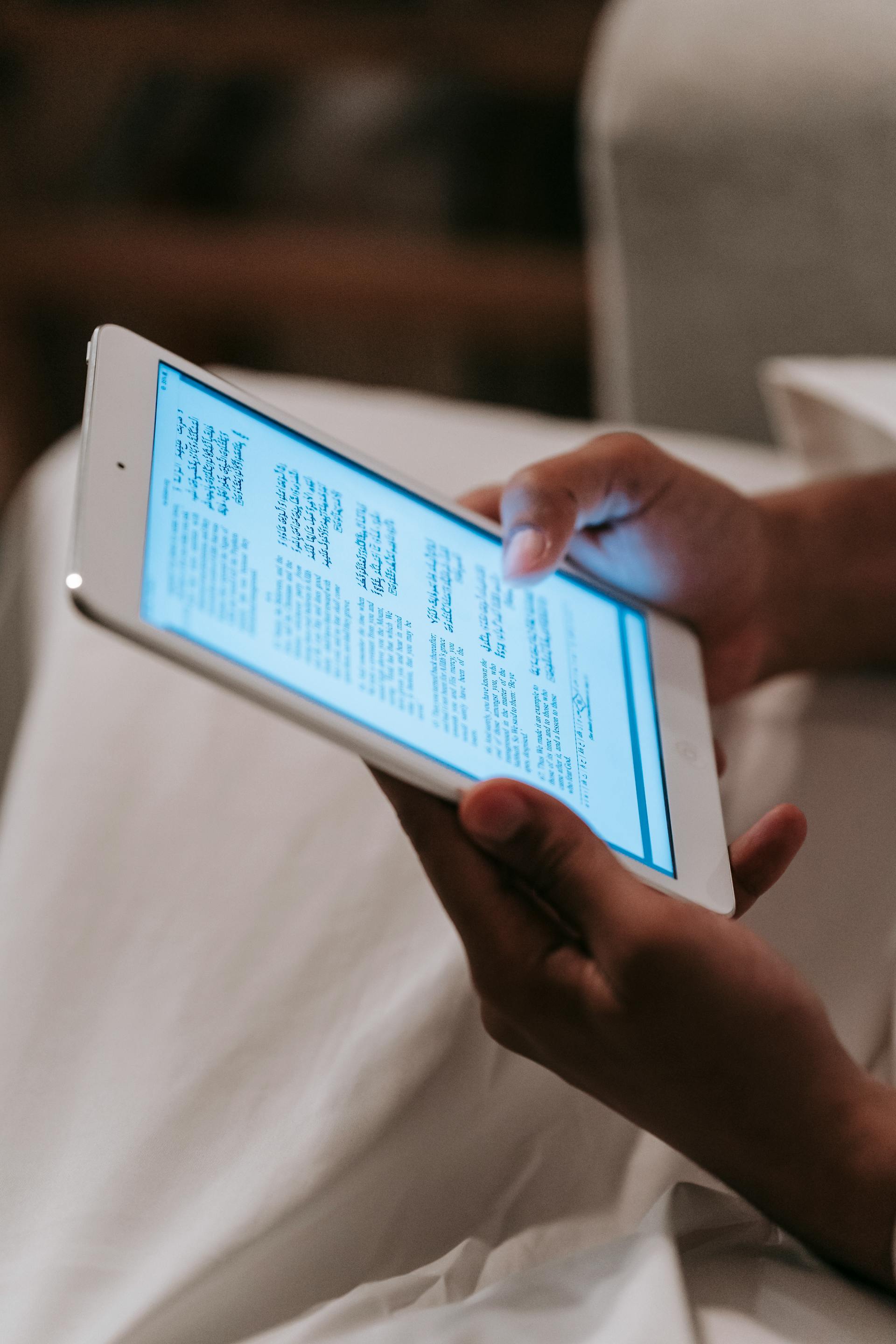 Eine Person, die ein Tablet mit leuchtendem Bildschirm hält und darauf schaut | Quelle: Pexels