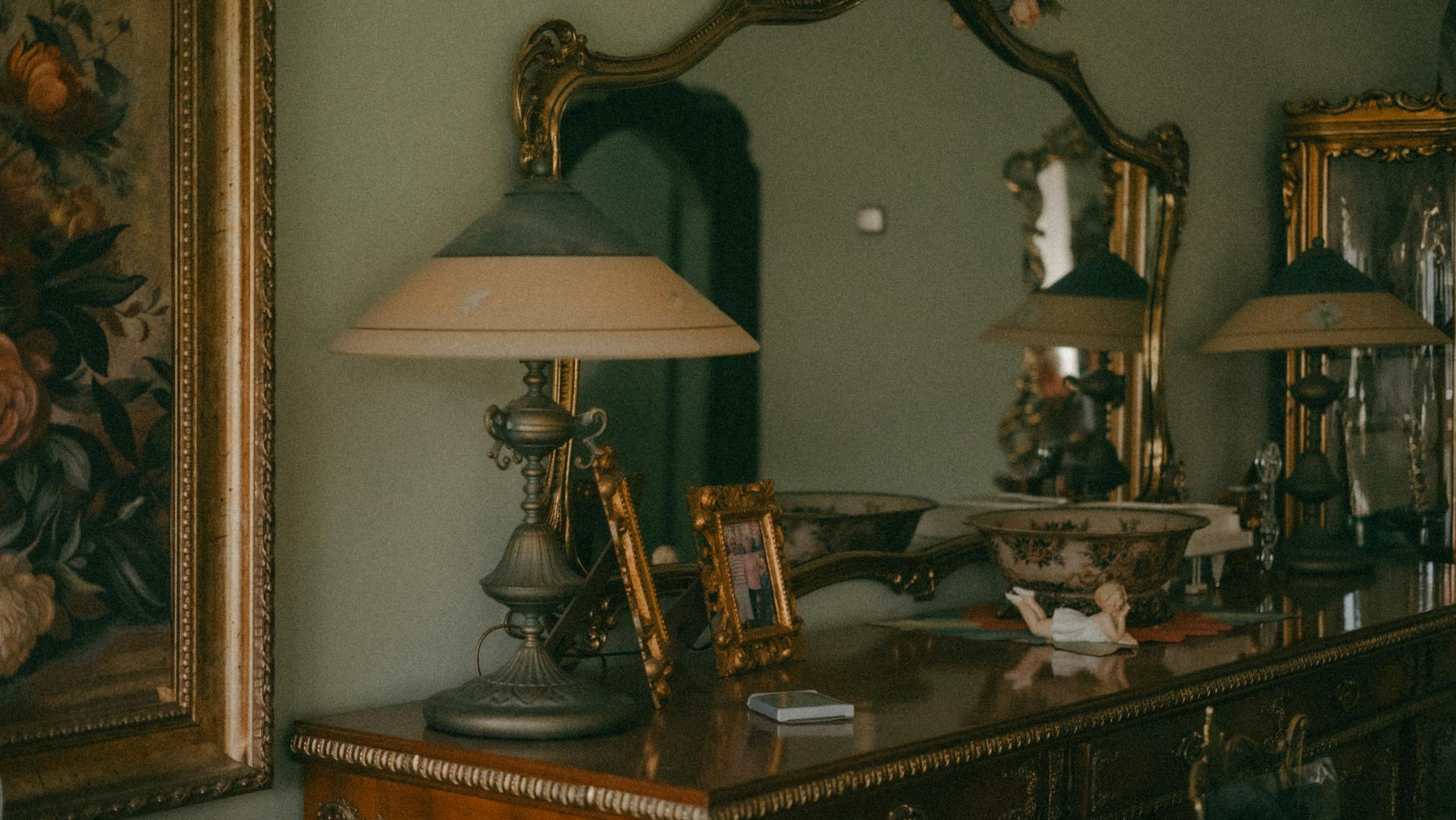 Eine hölzerne, antike Kommode mit einer Lampe und goldenen Rahmen oben drauf | Quelle: Pexels