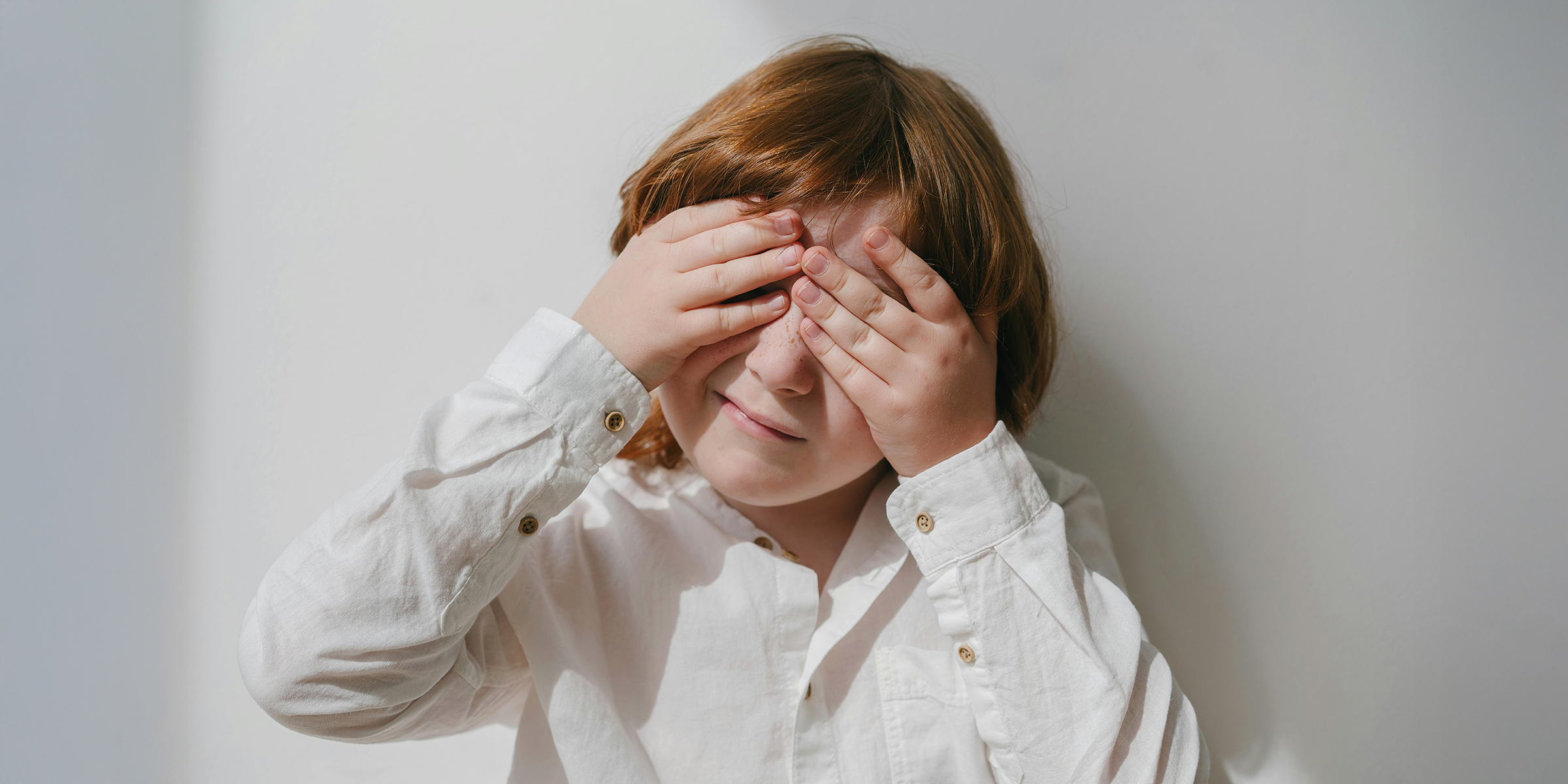 Junge versteckt sein Gesicht mit den Händen | Quelle: Pexels