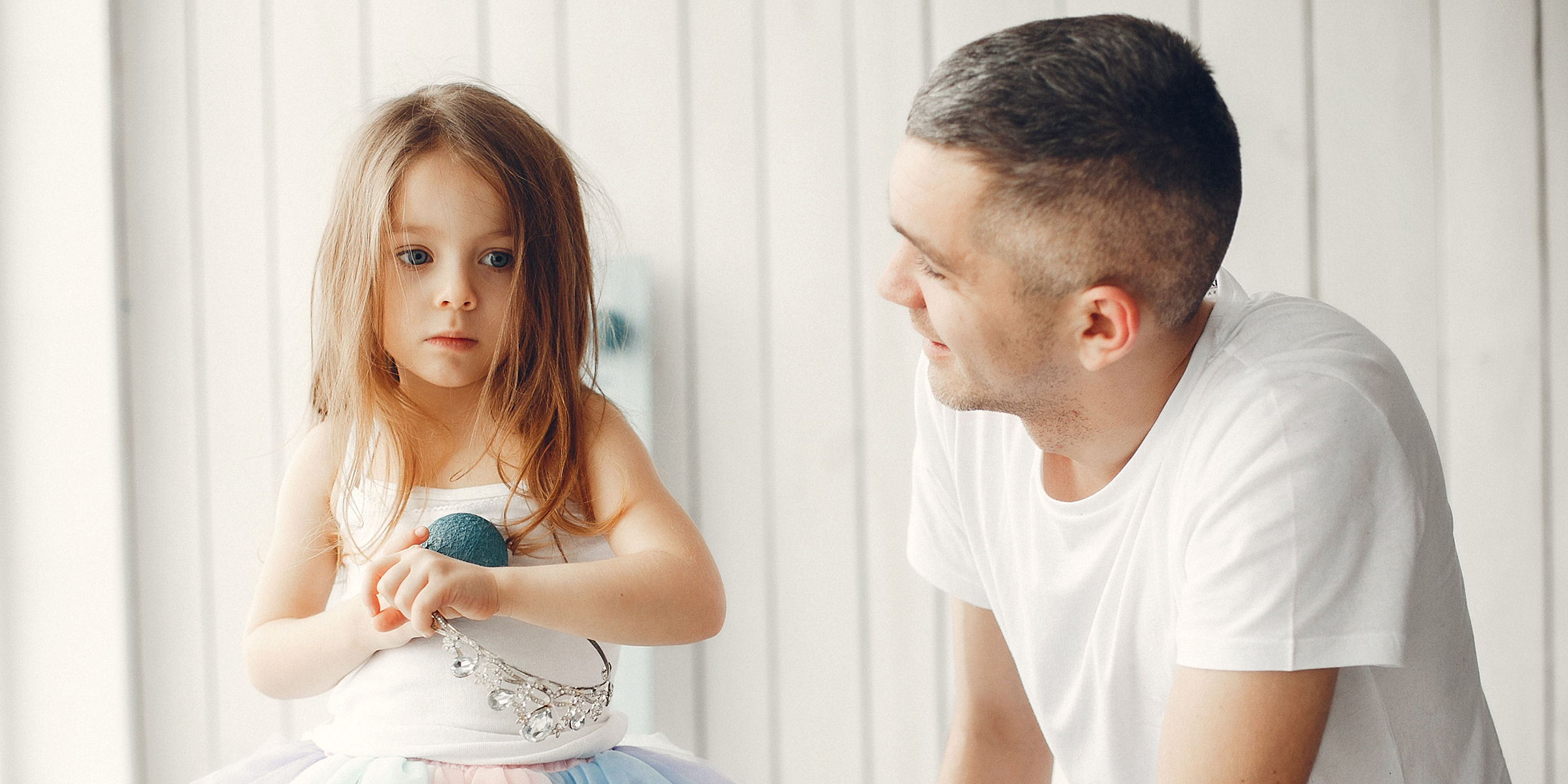 Ein Vater lächelt seine Tochter sanft an, während sie gedankenverloren vor sich hin starrt | Quelle: Shutterstock