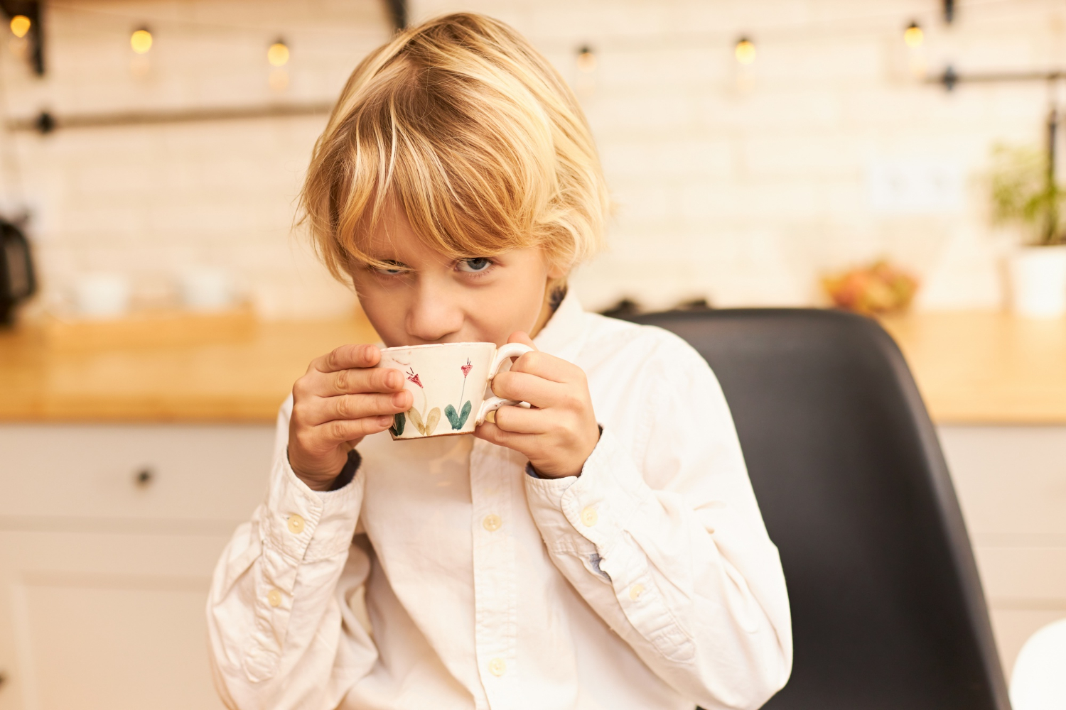 Ein kleiner Junge, der aus einer Keramiktasse trinkt und neugierig starrt | Quelle: Freepik