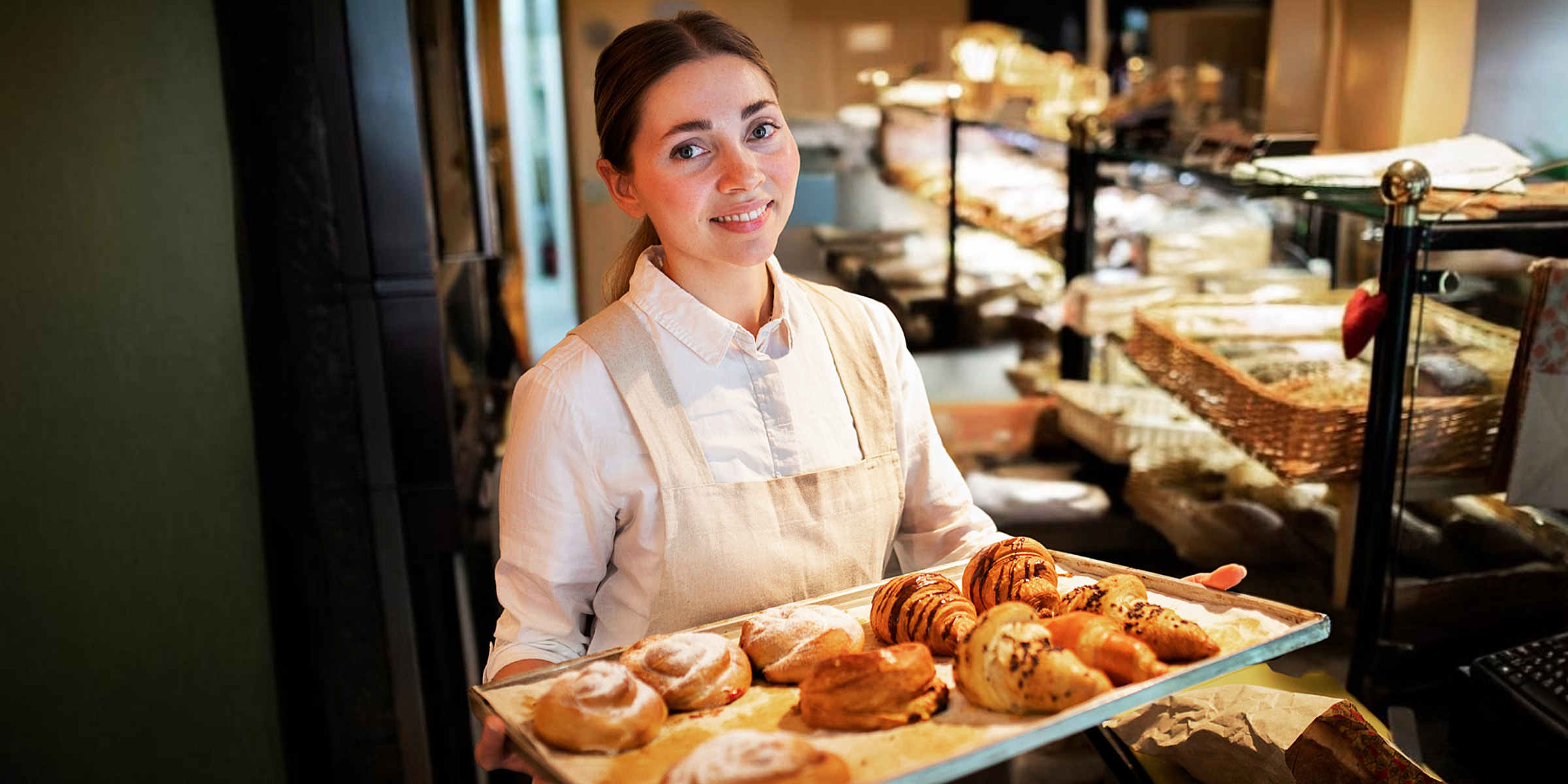 Eine Frau hält ein Tablett mit Gebäck in einer Bäckerei | Quelle: Freepik
