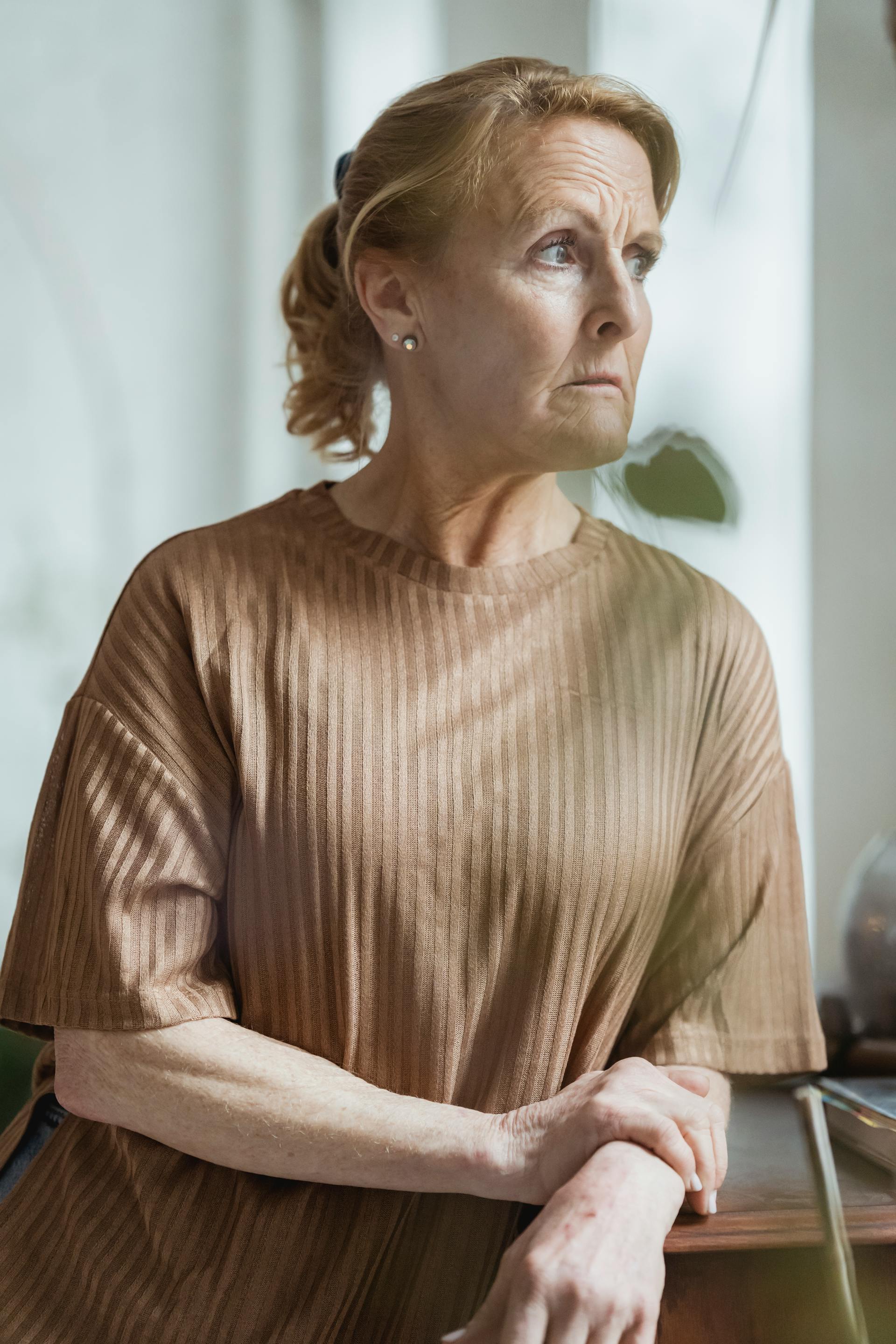 Eine reife Frau in einem braunen Pullover mit einem besorgten Gesichtsausdruck, die von der Front wegschaut | Quelle: Pexels
