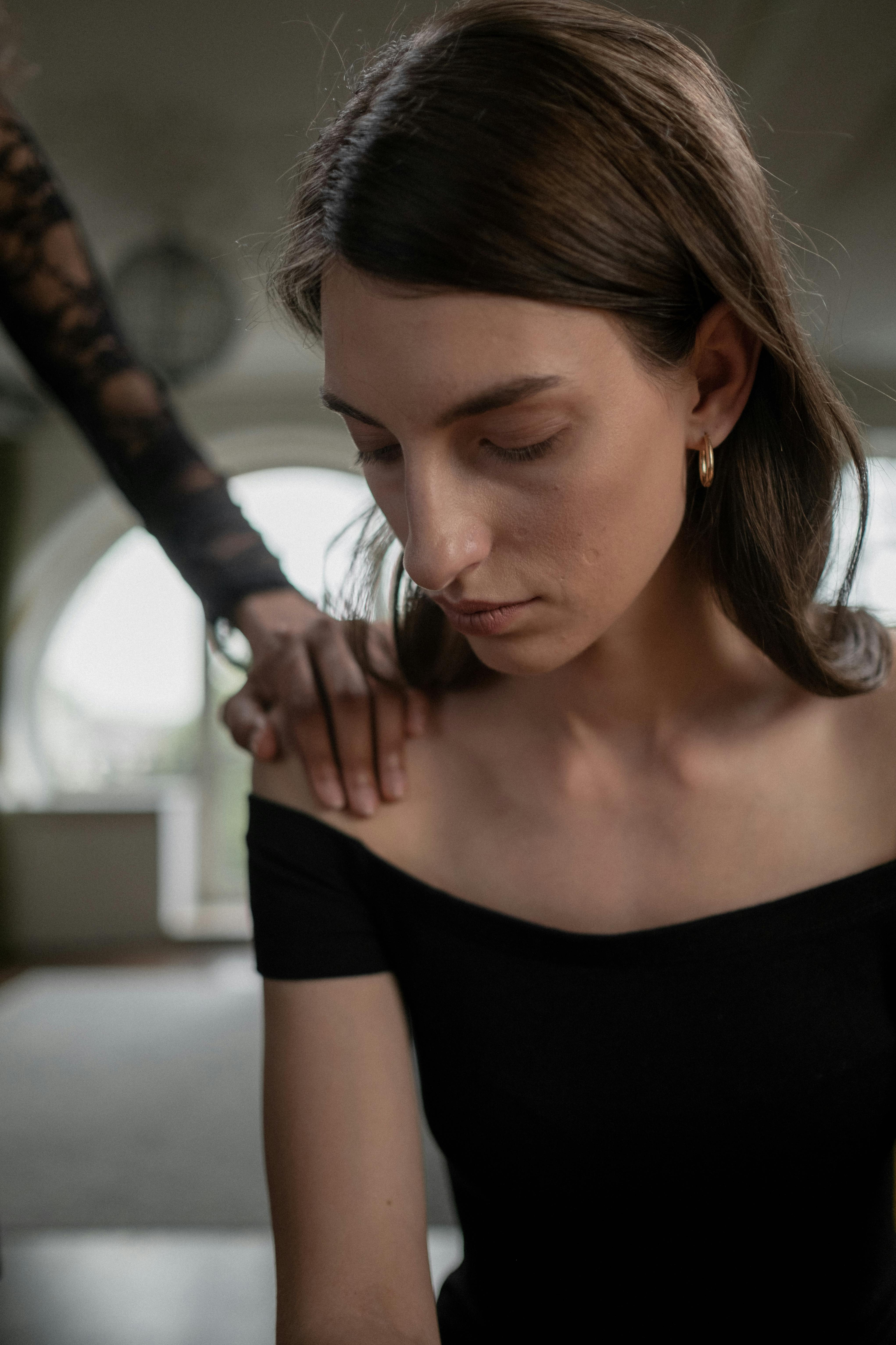 Eine traurige Frau schaut nach unten, während sie getröstet wird | Quelle: Pexels