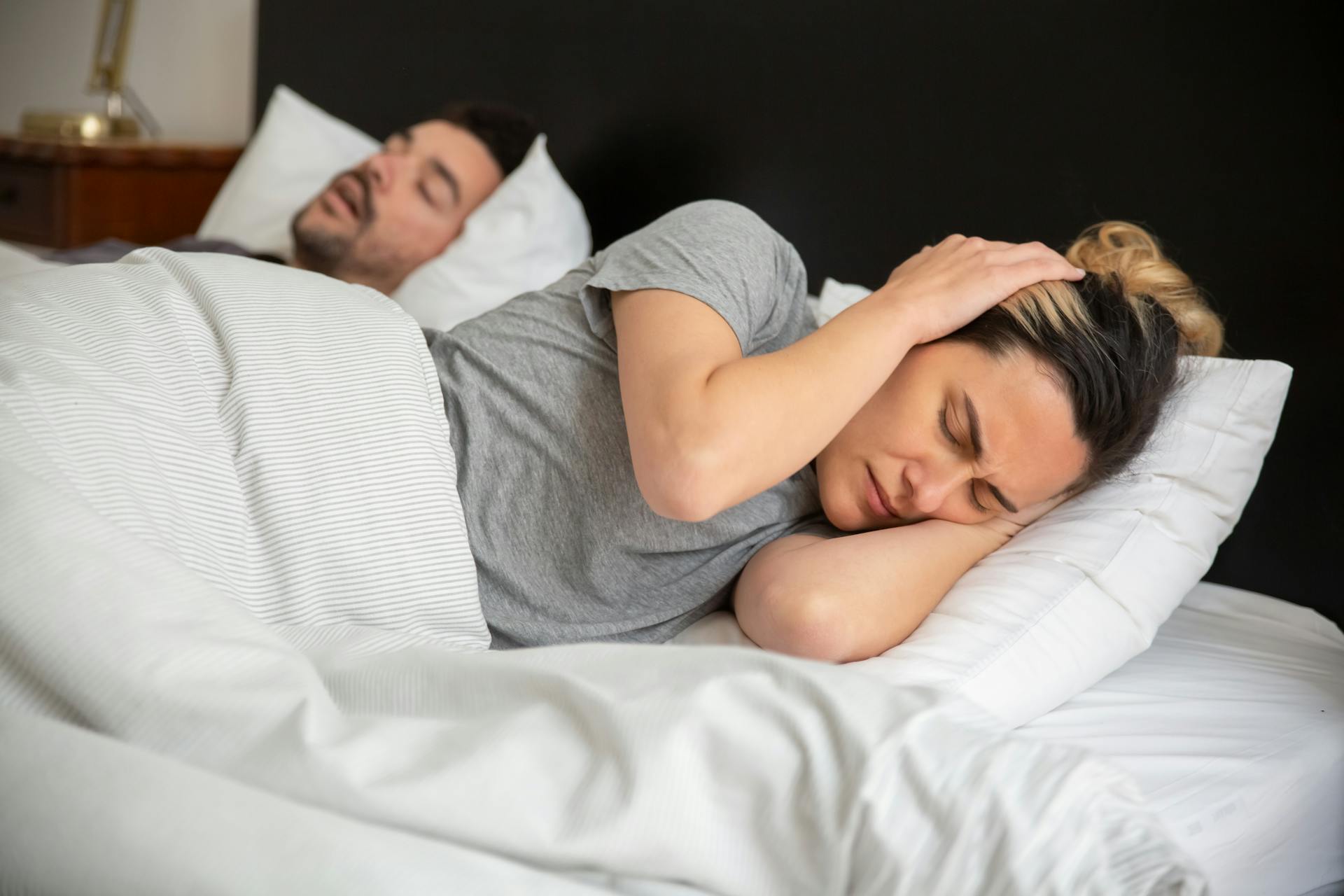 Eine Frau im Bett, die sich mit den Händen die Ohren zuhält | Quelle: Pexels