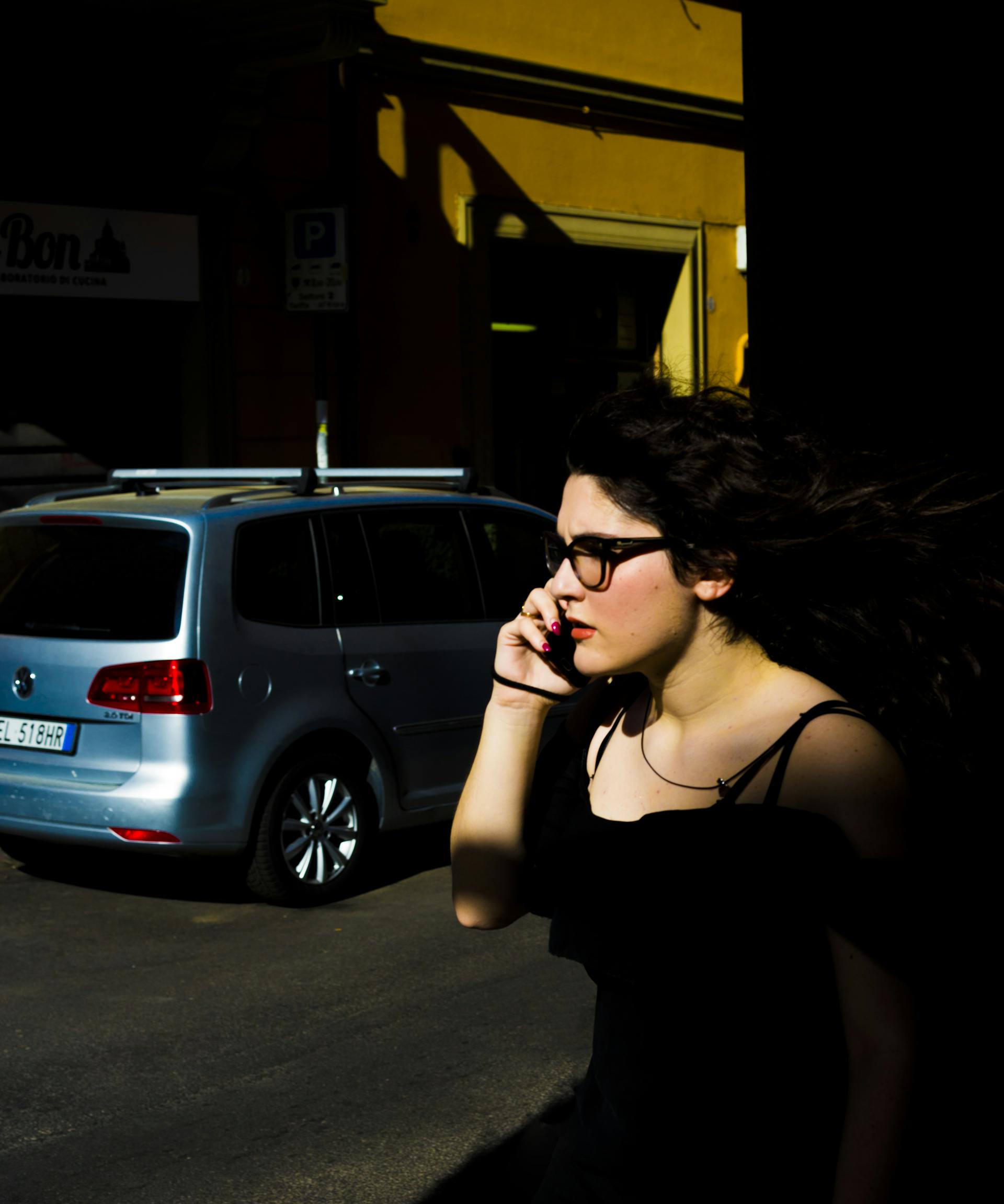 Eine Frau, die neben einem geparkten Fahrzeug steht und telefoniert | Quelle: Pexels