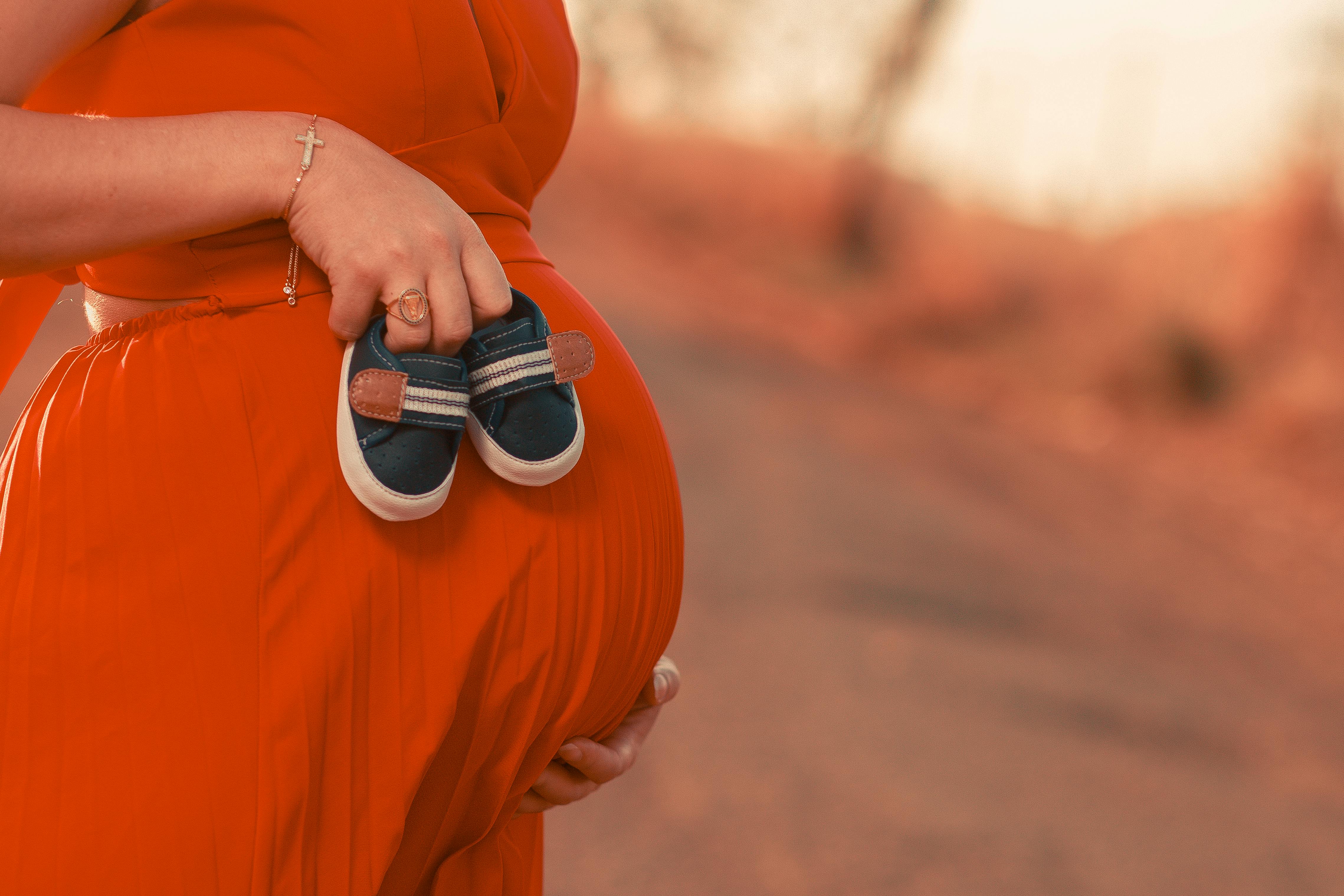 Eine schwangere Frau mit Babyschuhen | Quelle: Pexels