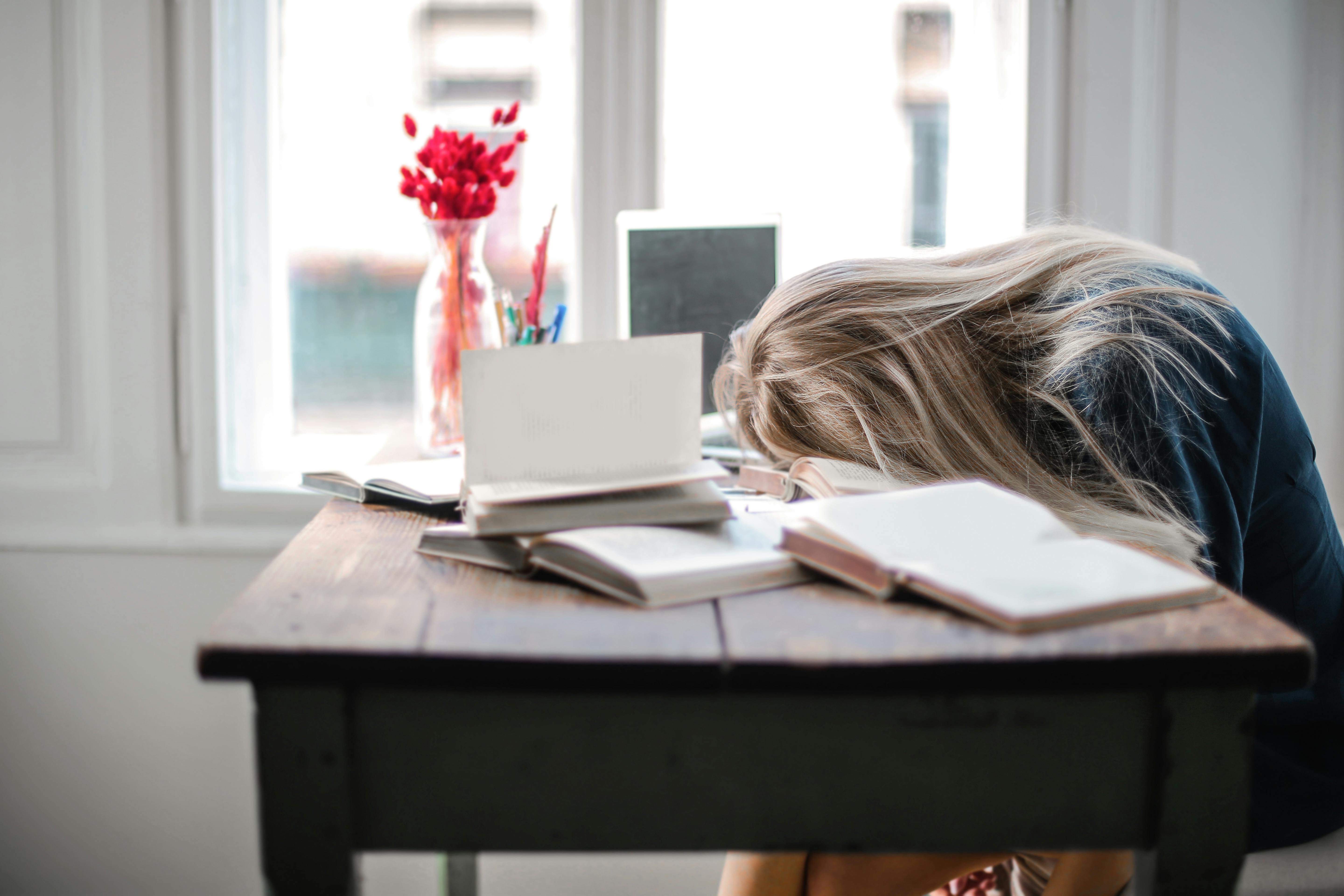 Eine erschöpfte Frau, die auf einem Schreibtisch schläft | Quelle: Pexels