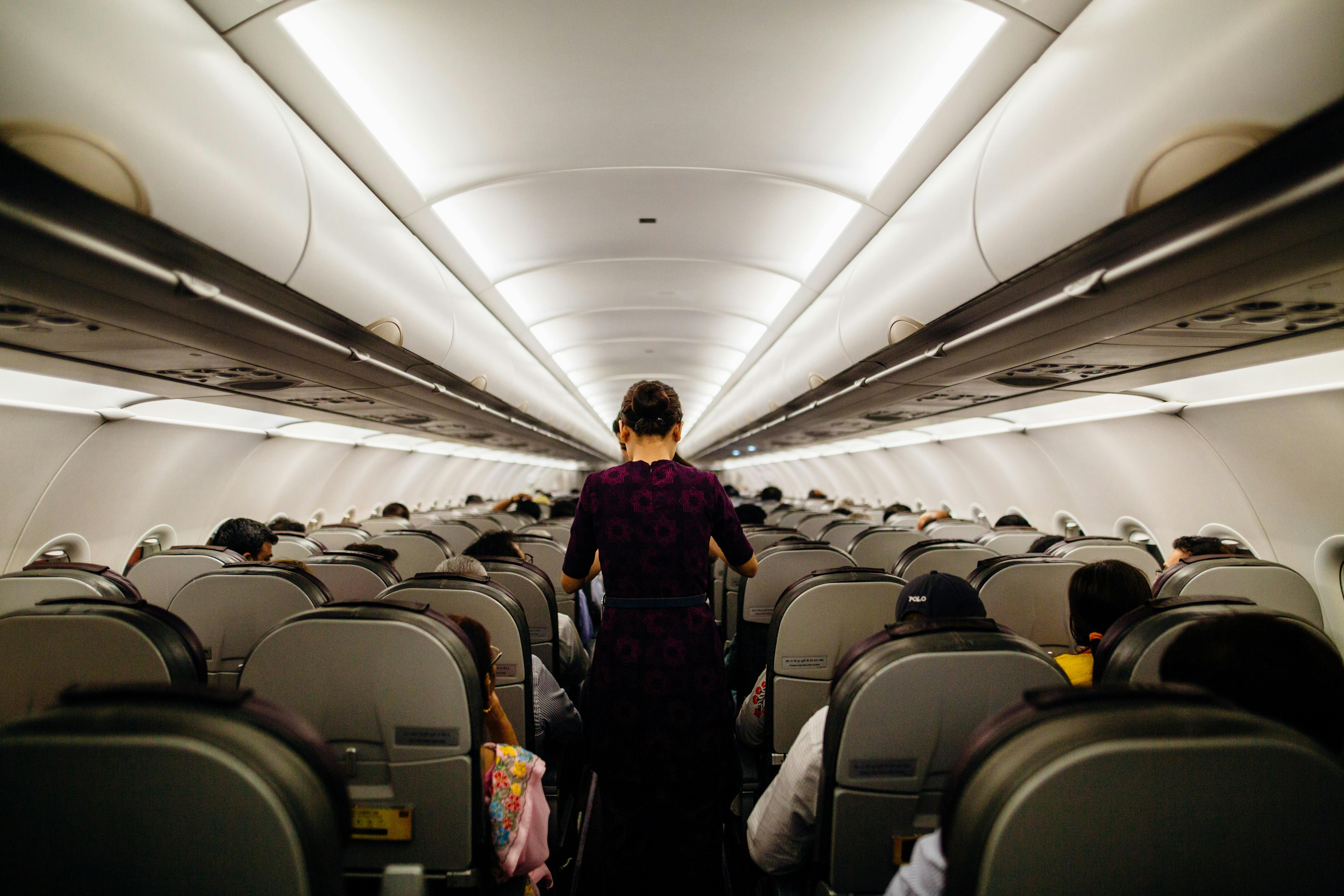 Eine Flugbegleiterin steht im Gang eines Flugzeugs | Quelle: Pexels