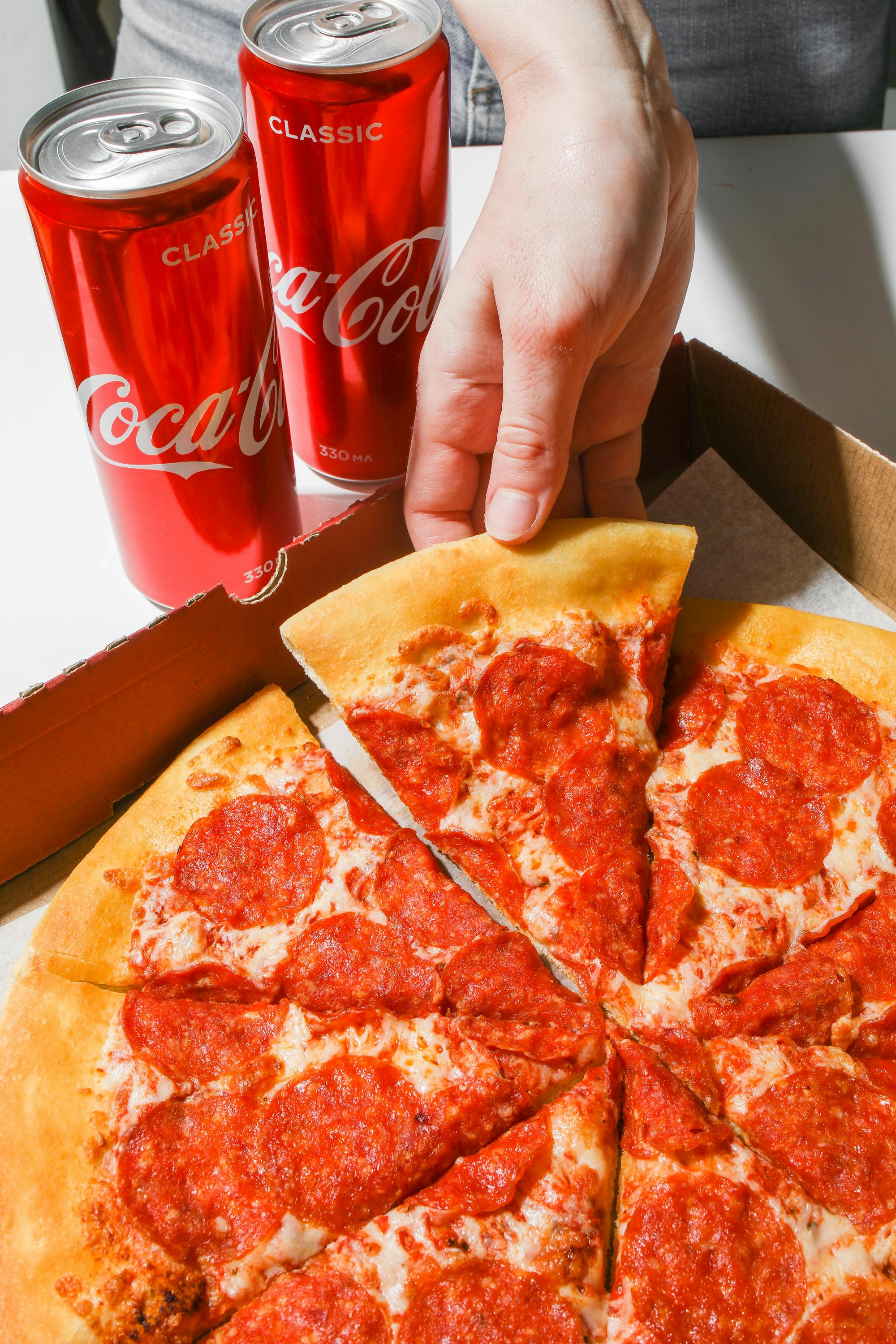 Eine Person, die nach einem Stück Pizza greift | Quelle: Pexels