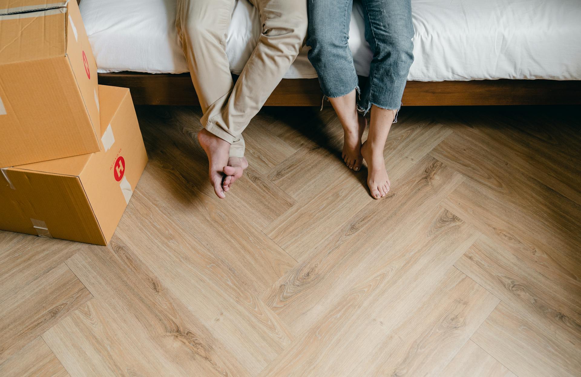 Eine Nahaufnahme eines Paares, das auf dem Bett sitzt und von Kartons umgeben ist | Quelle: Pexels