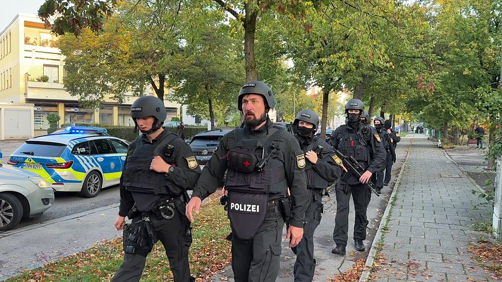 01. Oktober 2025, Bayern, München: Polizisten mit Schutzwesten gehen einen Fußweg entlang (Screenshot aus einem Video). Ein Brand in einem Einfamilienhaus in München hat einen Großeinsatz von Polizei und Feuerwehr ausgelöst. | Quelle: © Getty Images