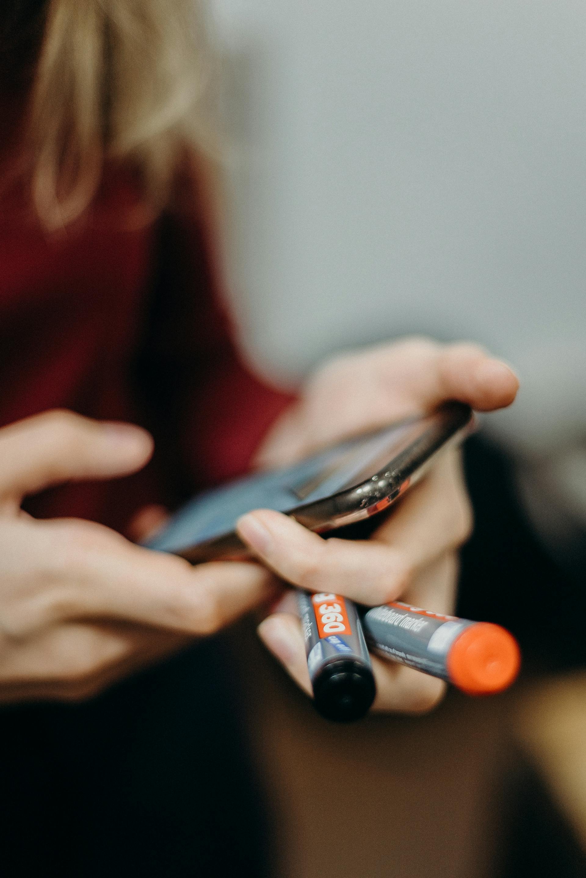 Eine Frau hält ein Smartphone und zwei Marker in der Hand | Quelle: Pexels