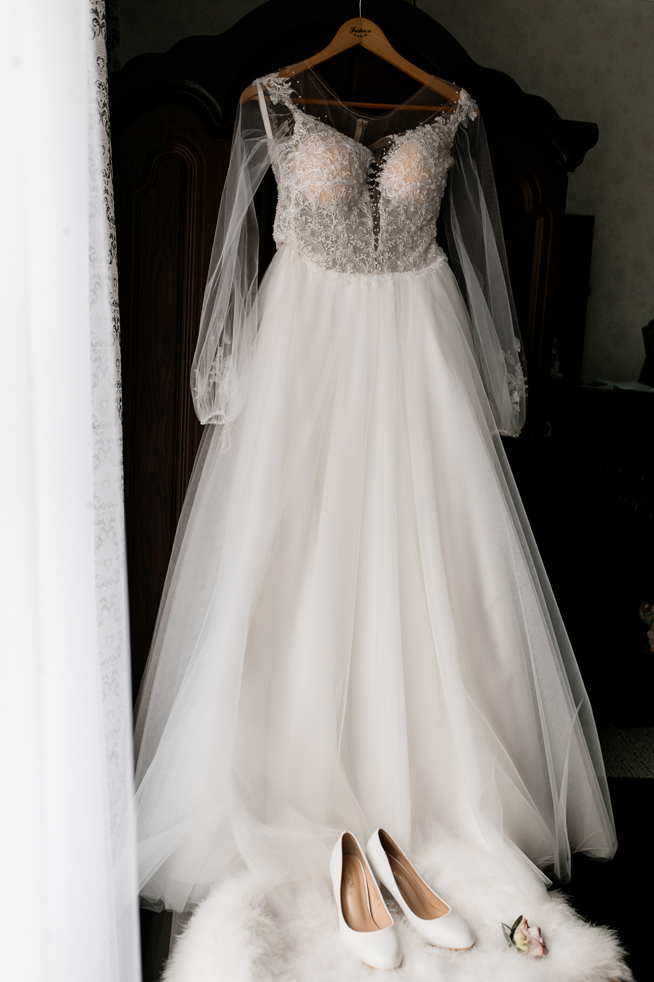 Ein Brautkleid in einem Kleiderbügel und weiße Absätze, die auf einem Pelzpuff liegen | Quelle: Freepik