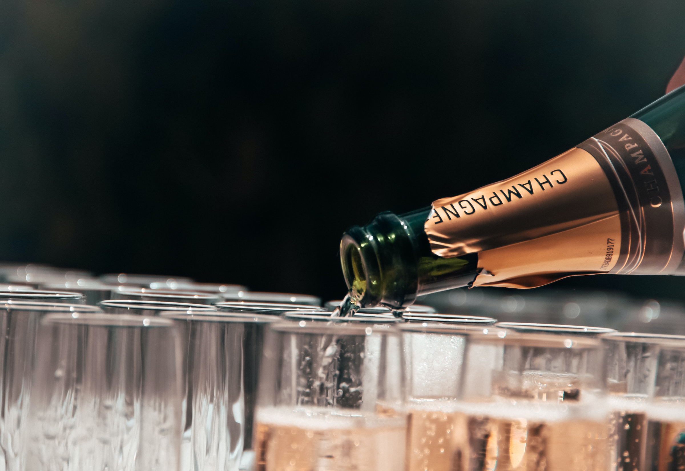 Eine Nahaufnahme einer Person, die Champagner in Gläser einschenkt | Quelle: Unsplash