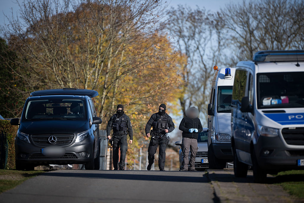 06. November 2025, Mecklenburg-Vorpommern, Güstrow: Polizeibeamte überqueren während einer Hausdurchsuchung in Reimershagen die Straße. | Quelle: Getty Images