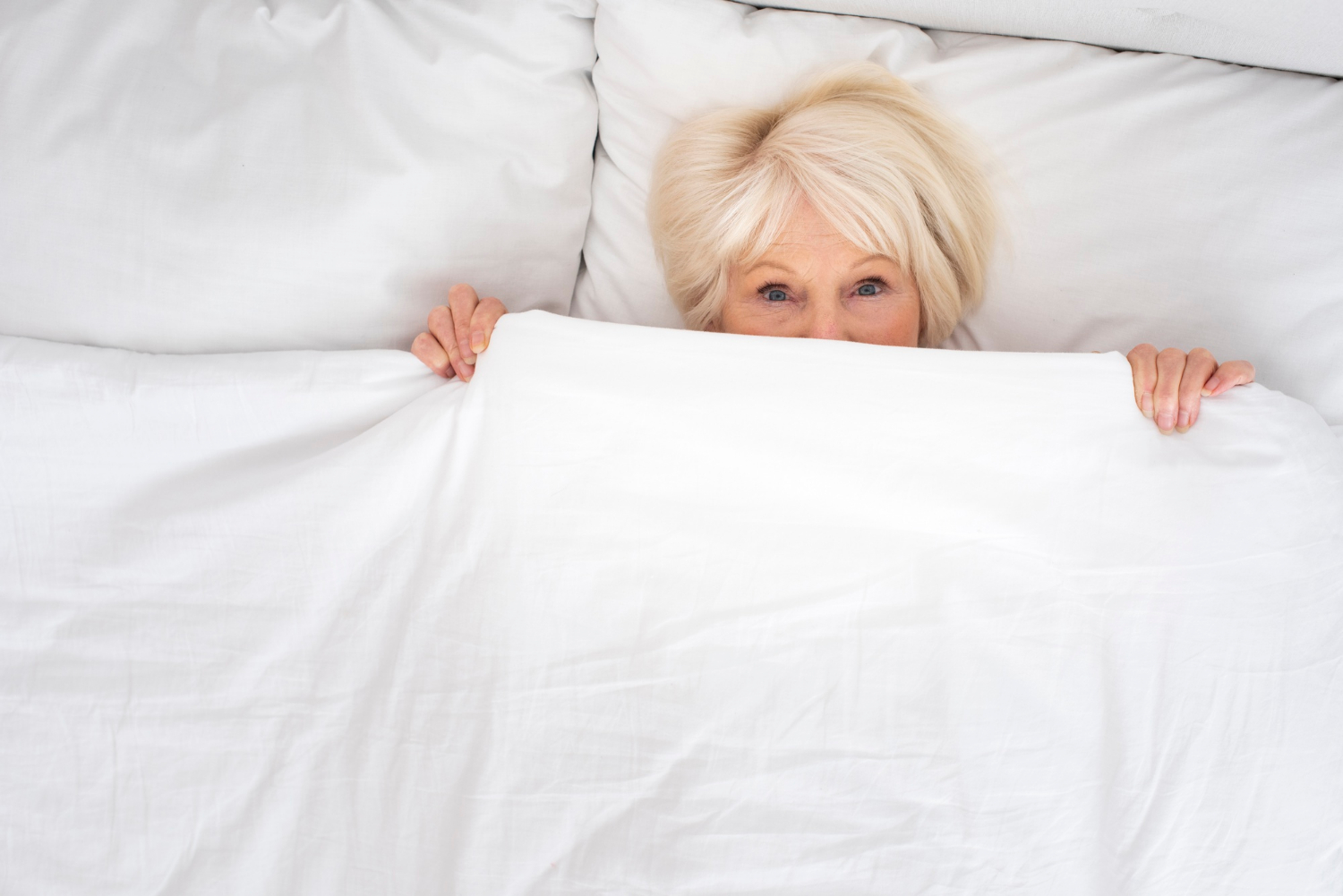 Eine erschrockene ältere Frau in ihrem Bett | Quelle: Freepik