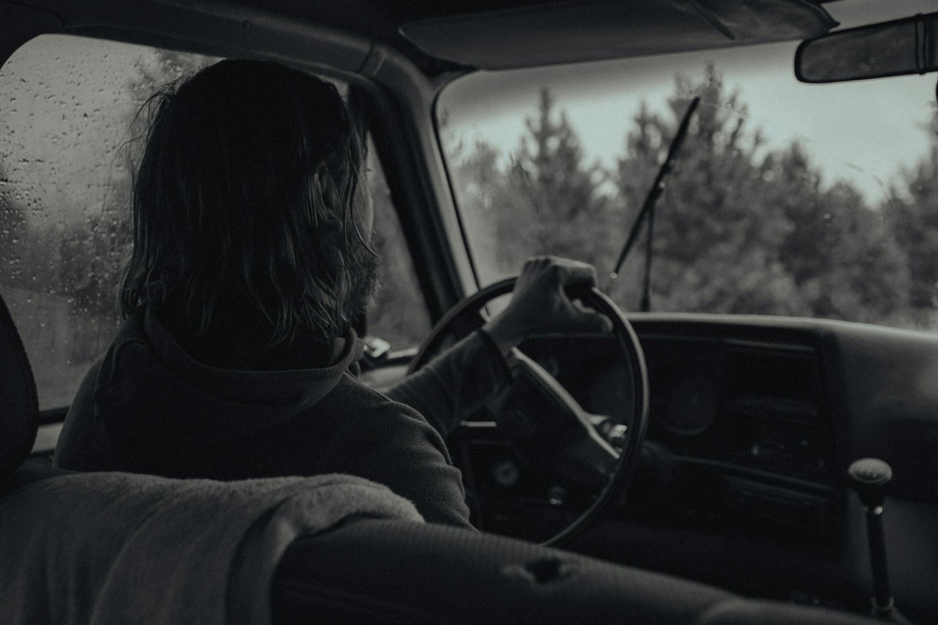 Ein Graustufenfoto von einer Frau, die im Regen Auto fährt | Quelle: Pexels