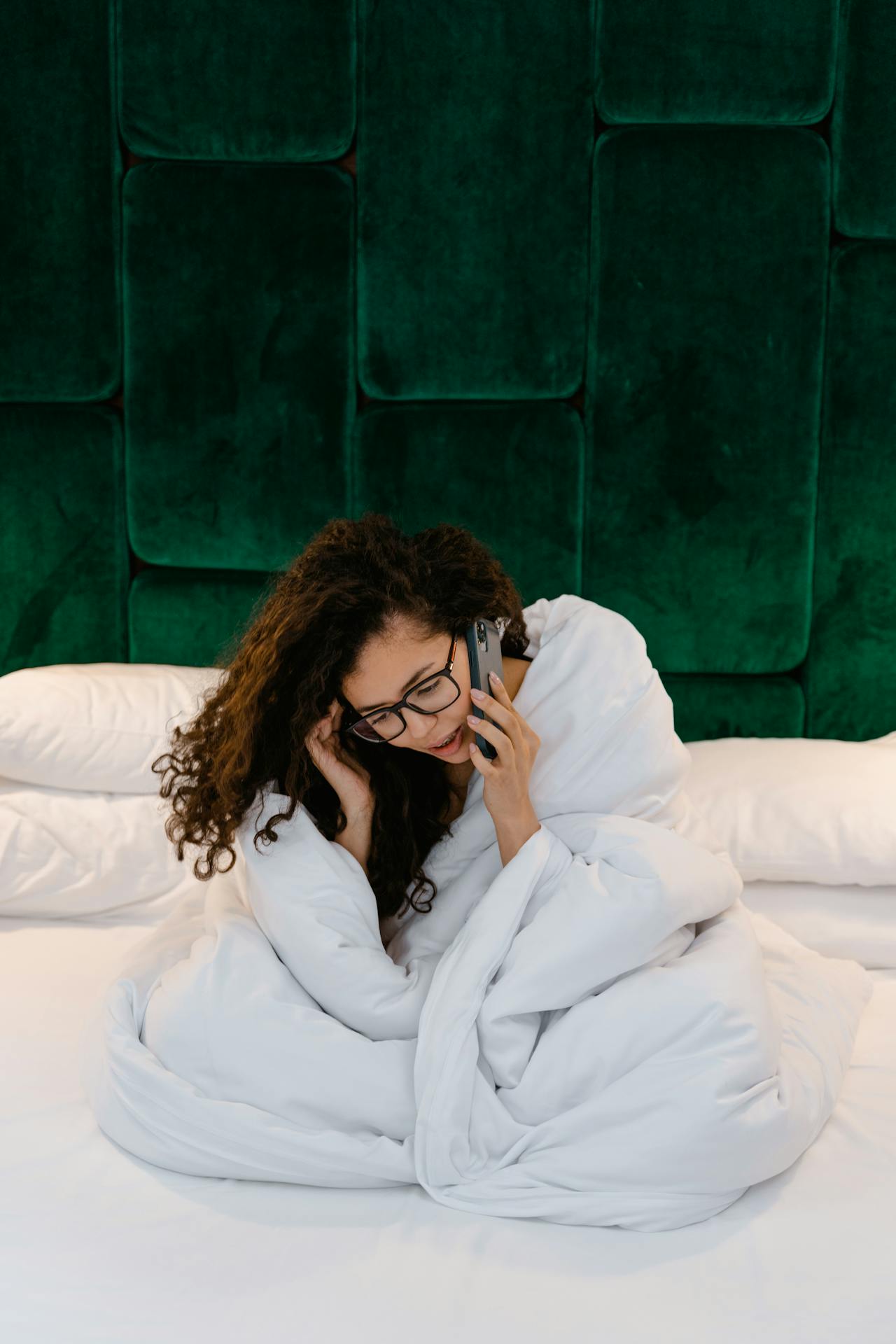 Eine Frau, die auf ihrem Bett sitzt und telefoniert | Quelle: Pexels