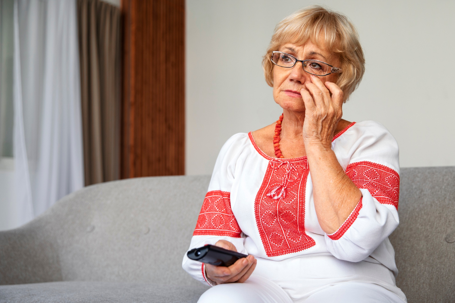 Eine traurige ältere Frau hält eine TV-Fernbedienung | Quelle: Freepik