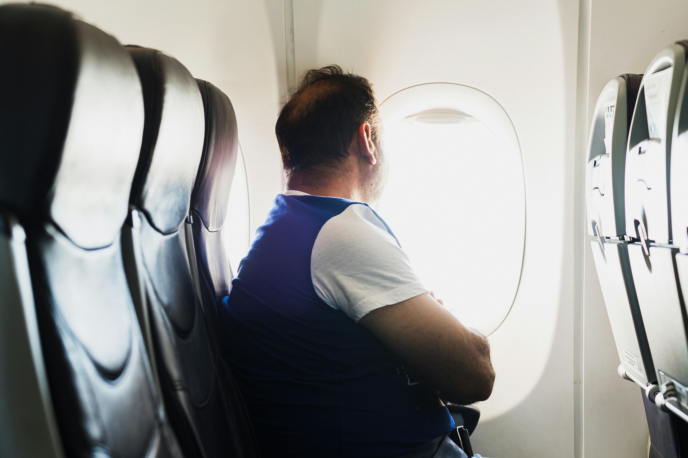 Mann in einem Flugzeug, der aus dem Fenster schaut | Quelle: Unsplash