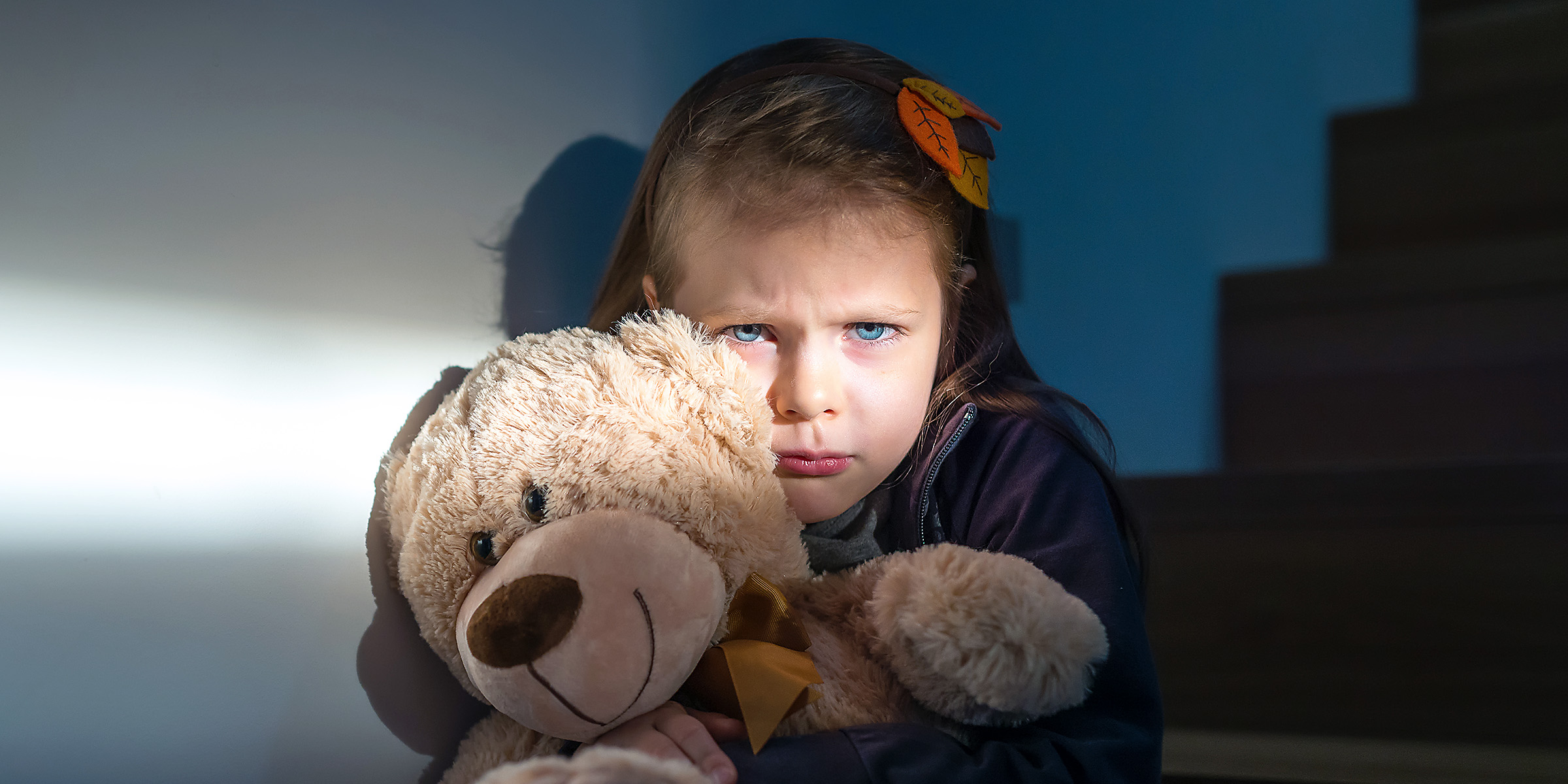 Ein trauriges und verängstigtes kleines Mädchen, das einen Teddybär umklammert | Quelle: Shutterstock