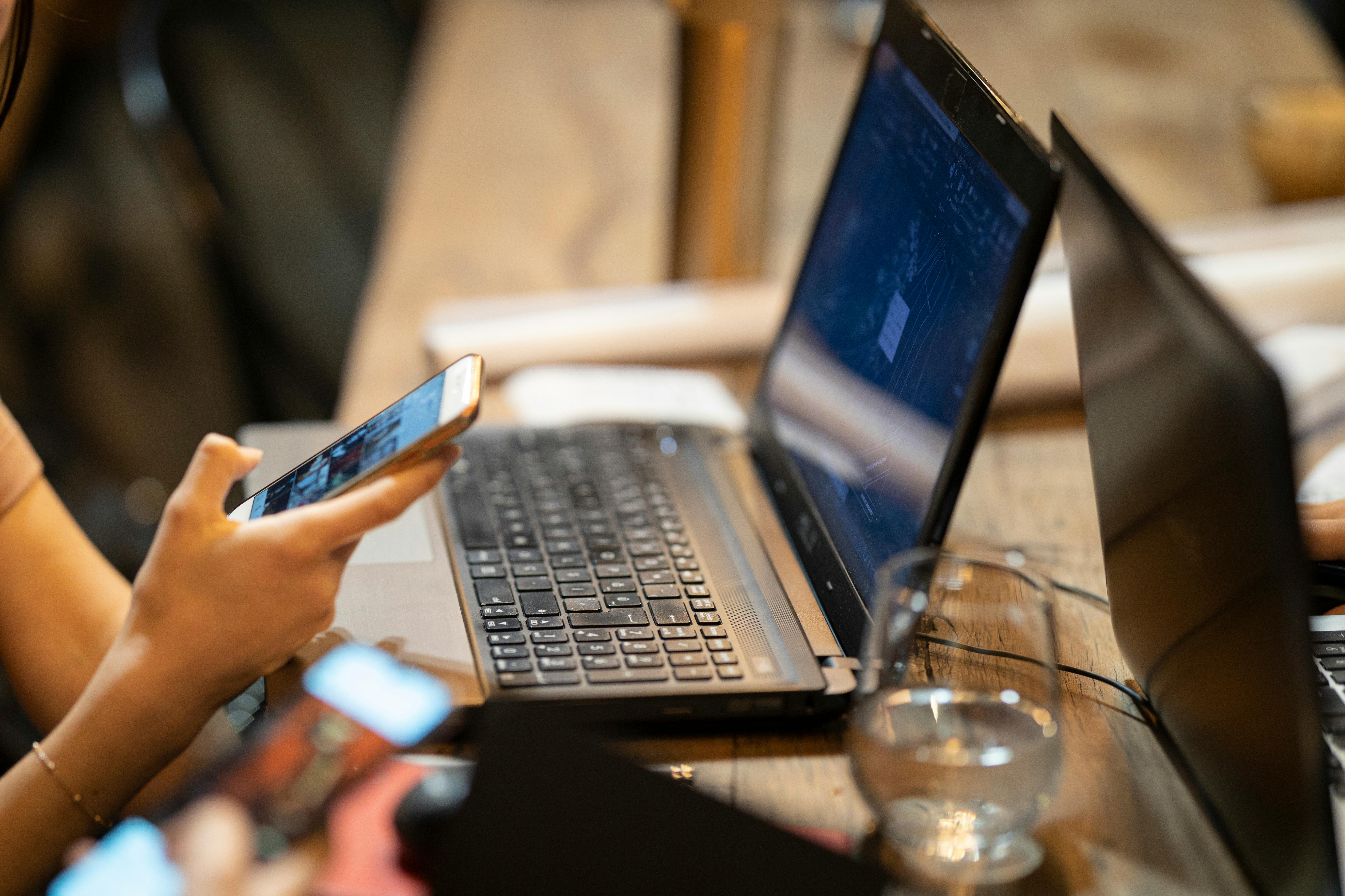 Telefonierende Person mit Laptop auf dem Schreibtisch | Quelle: Pexels