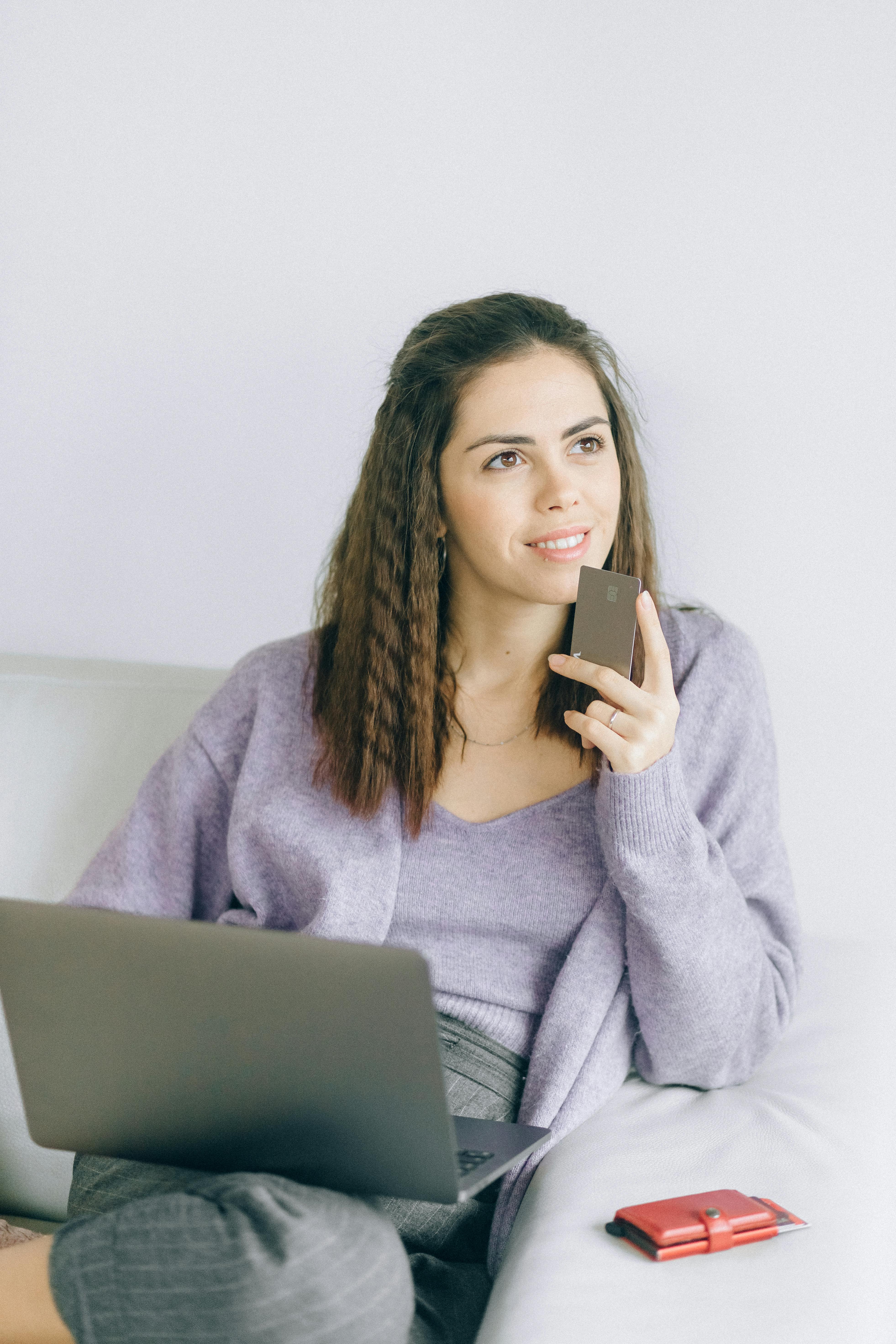 Eine Frau hält eine Bankkarte und einen Laptop in der Hand | Quelle: Pexels